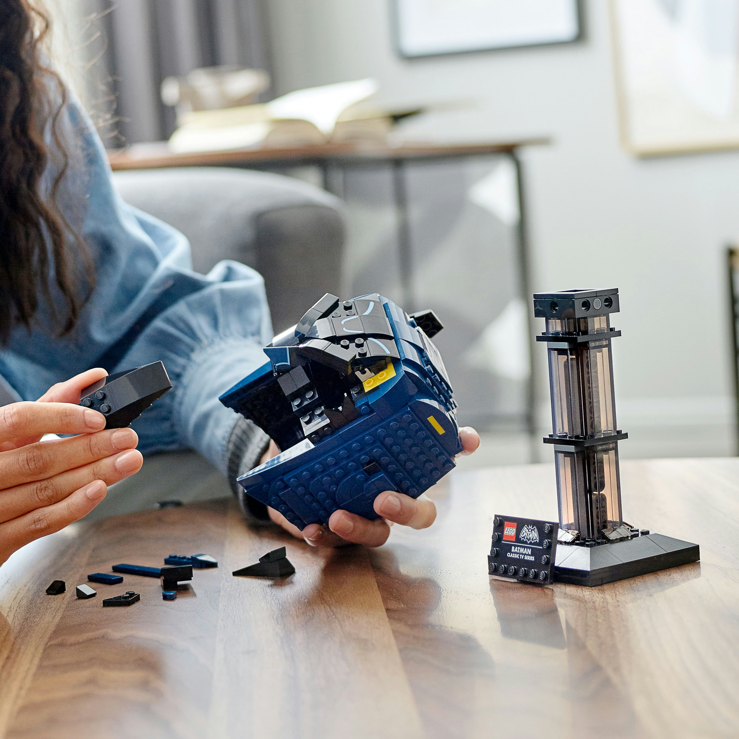 Ręce składają ciemnoniebieski zestaw LEGO z czarnym elementem obok.