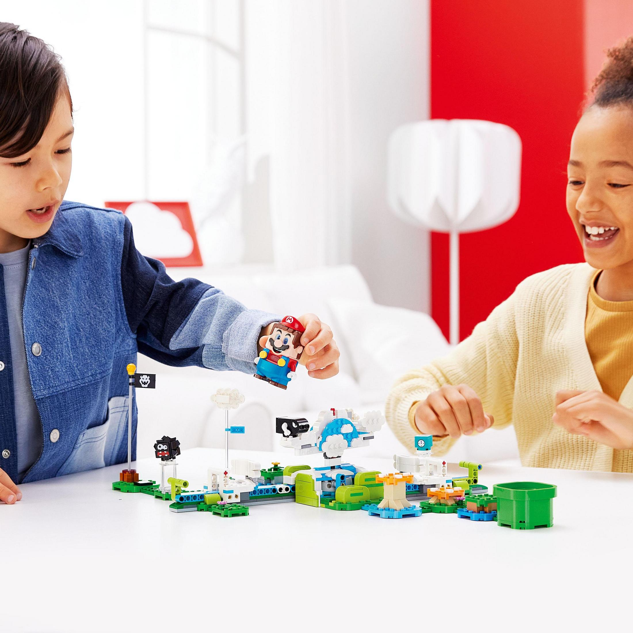 Zwei Kinder spielen mit einem Lego-Set. Mario und andere Lego-Charaktere befinden sich auf einer grünen Lego-Oberfläche.