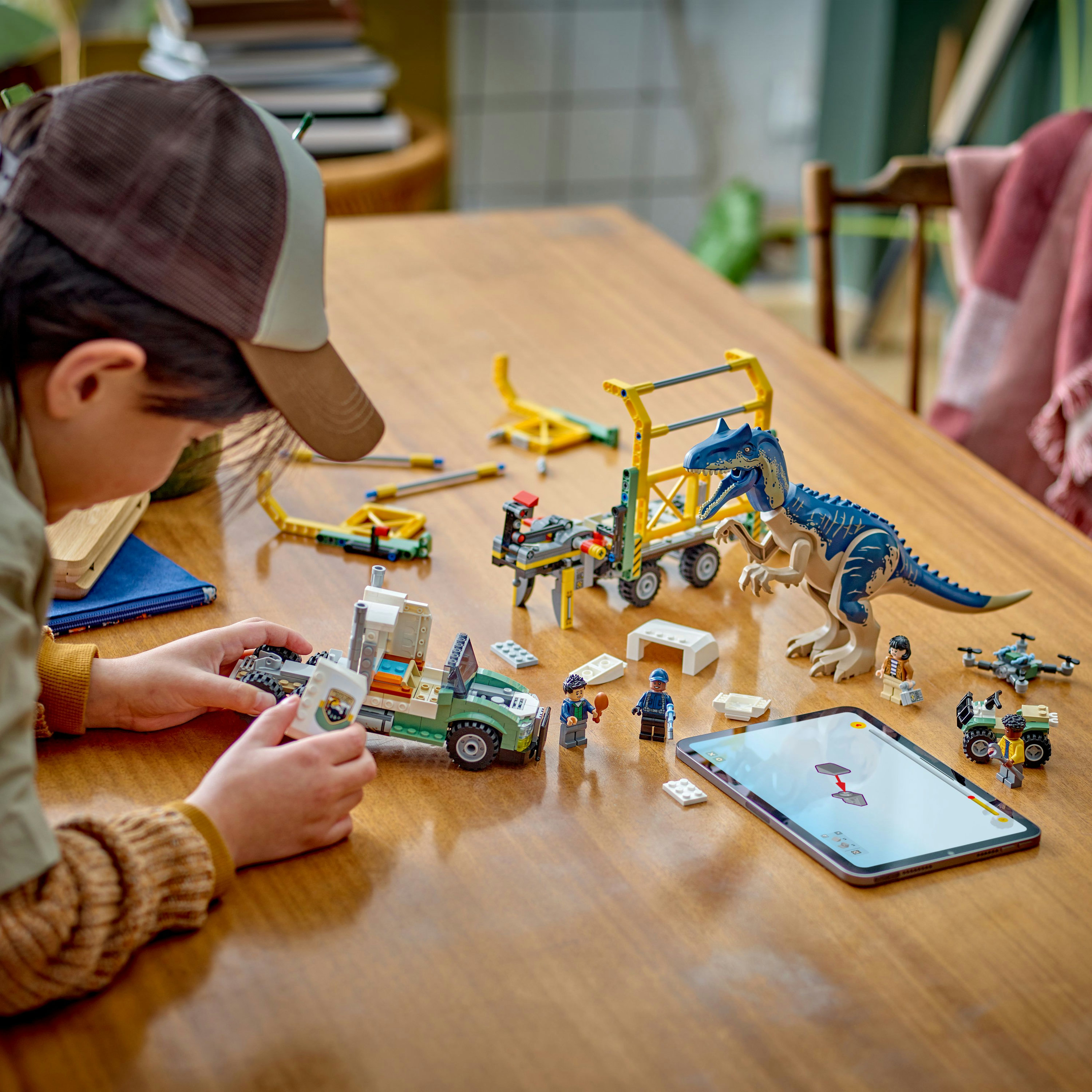 Osoba składająca zestaw transportu dinozaurów Lego. Widoczny niebieski dinozaur i figurki Lego.