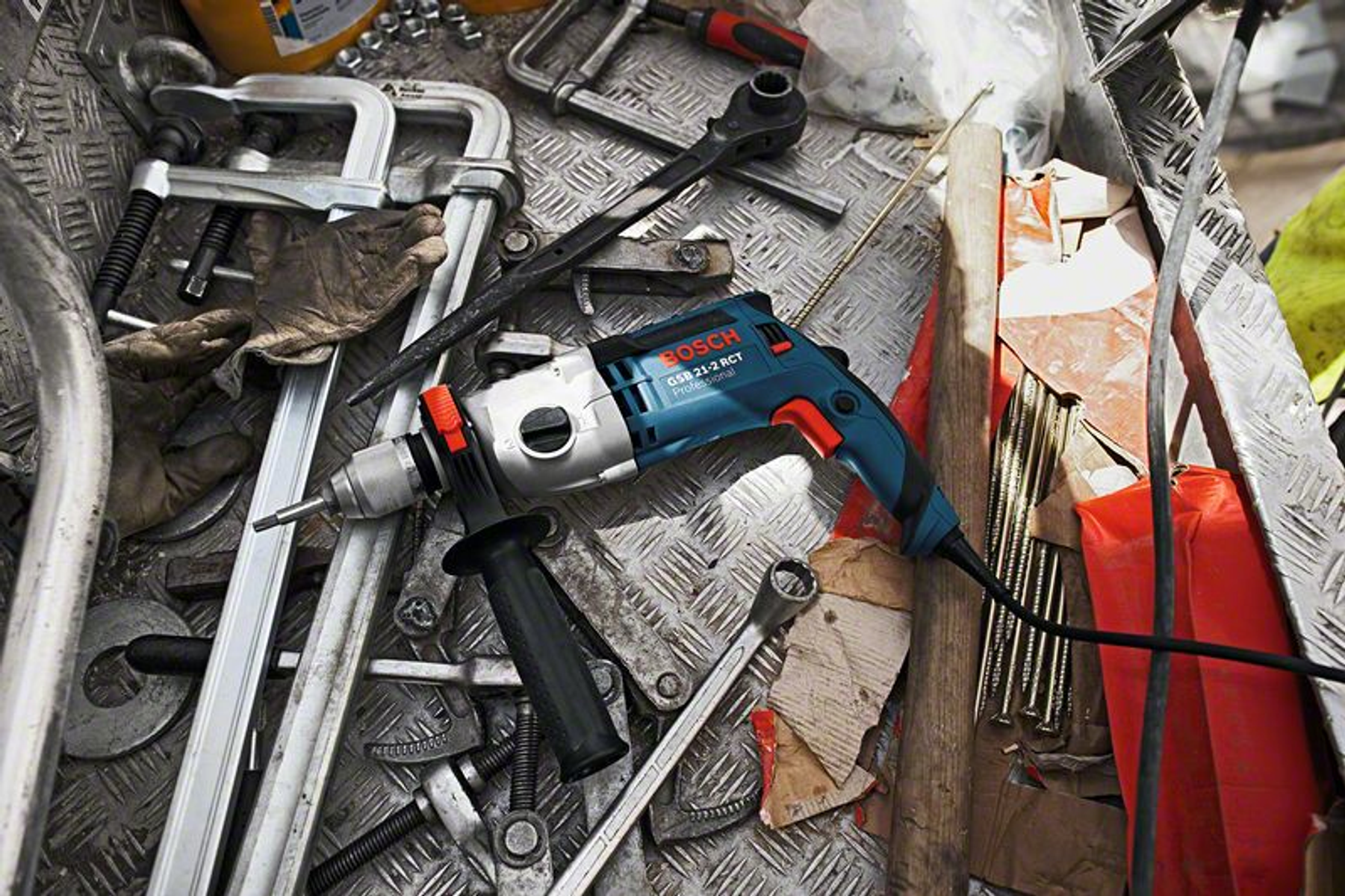 Bir Bosch matkabı, metal bir yüzeyde anahtarlar ve kelepçeler gibi aletlerin arasında yatıyor.