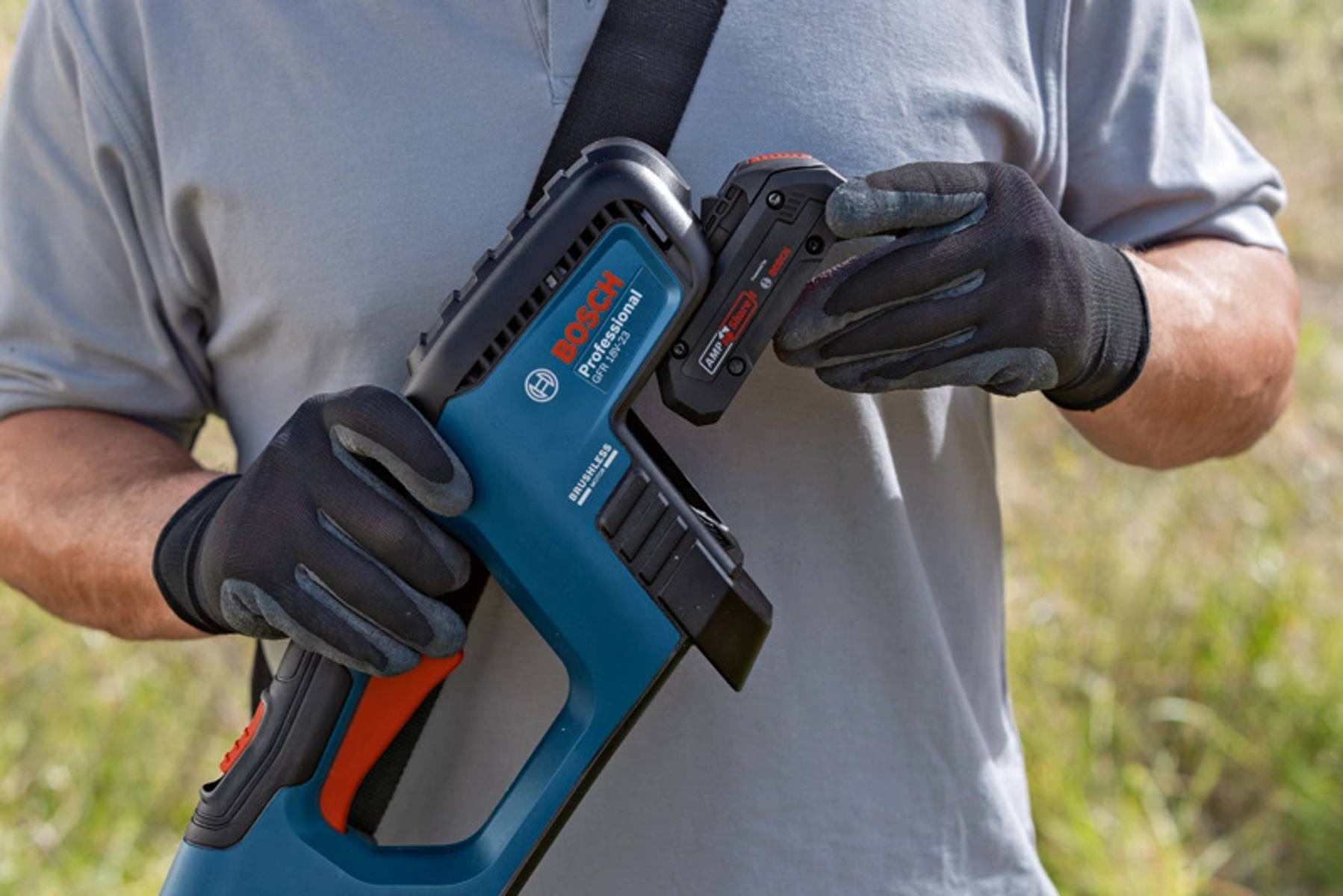 Eine Person mit Handschuhen hält ein schwarz-blaues Elektrowerkzeug und einen Akku.