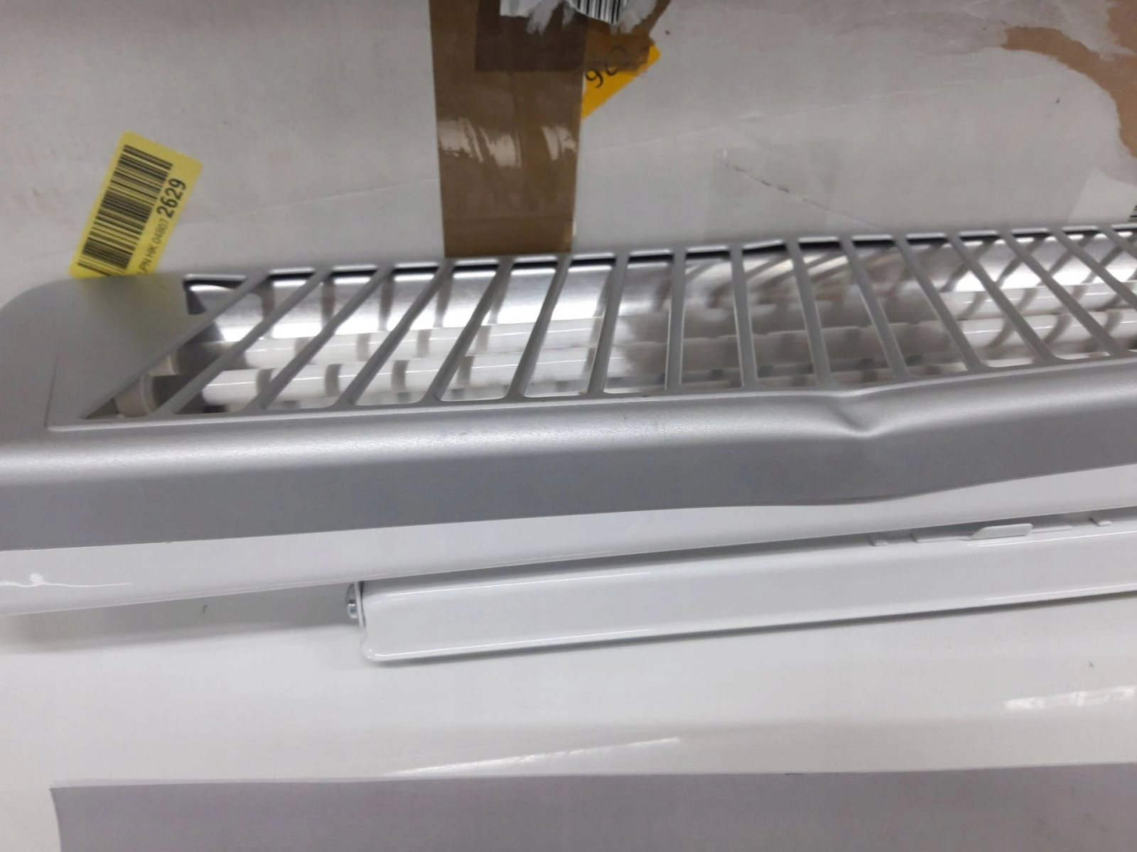 Zbliżenie srebrnej kratki wentylacyjnej z lekko zagiętym fragmentem.