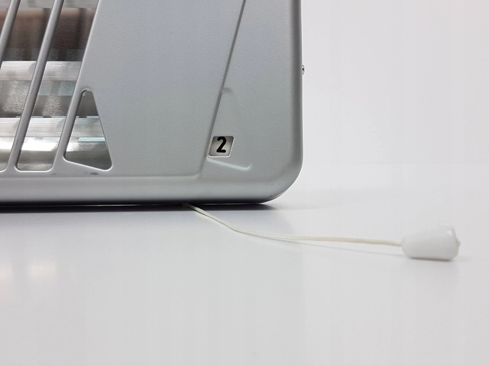 Srebrne urządzenie z białym przewodem i białym sznurkiem na białym tle.