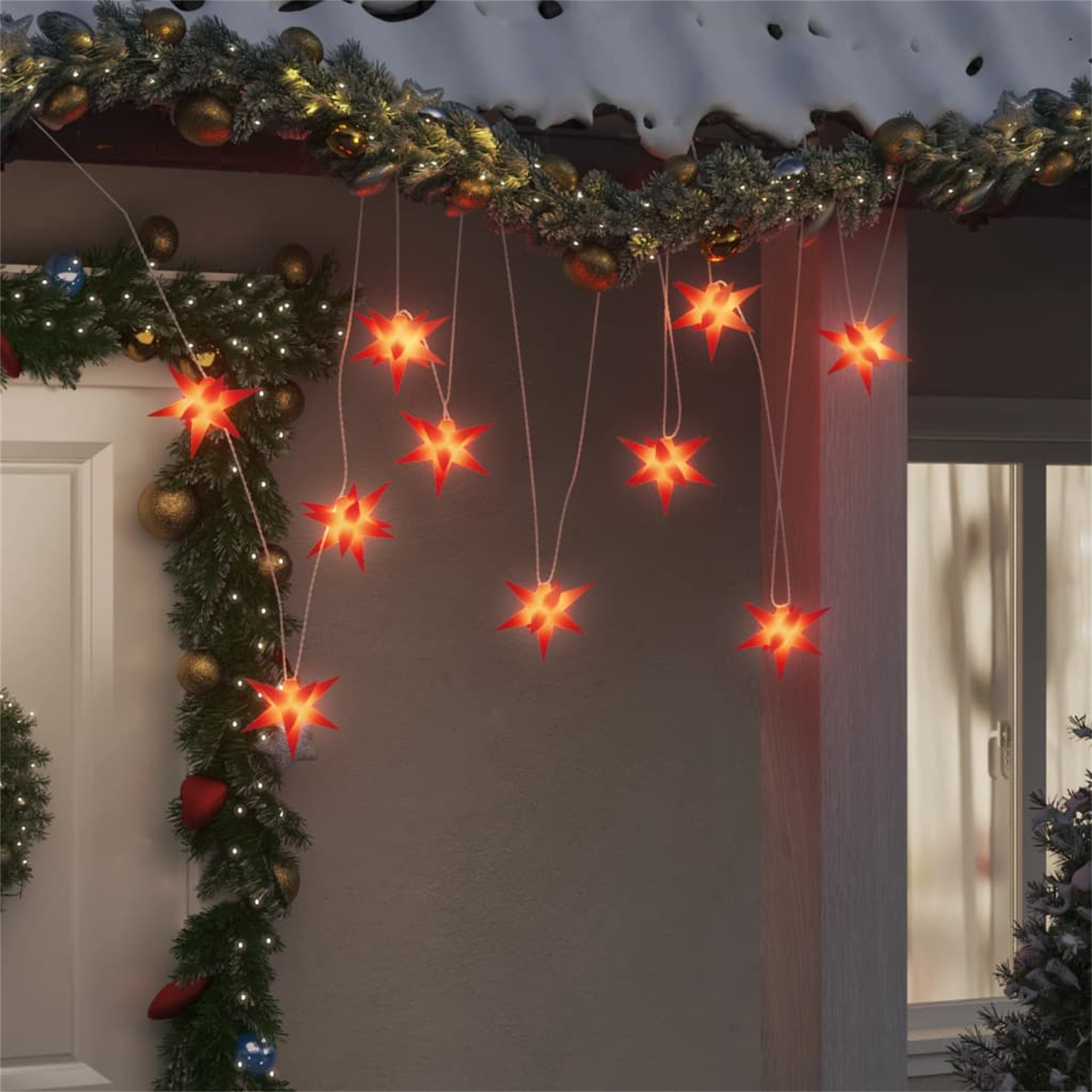 Das Bild zeigt ein Hausäußeres mit Weihnachtsbeleuchtung und sternförmigen Dekorationen, die vom Dach hängen.