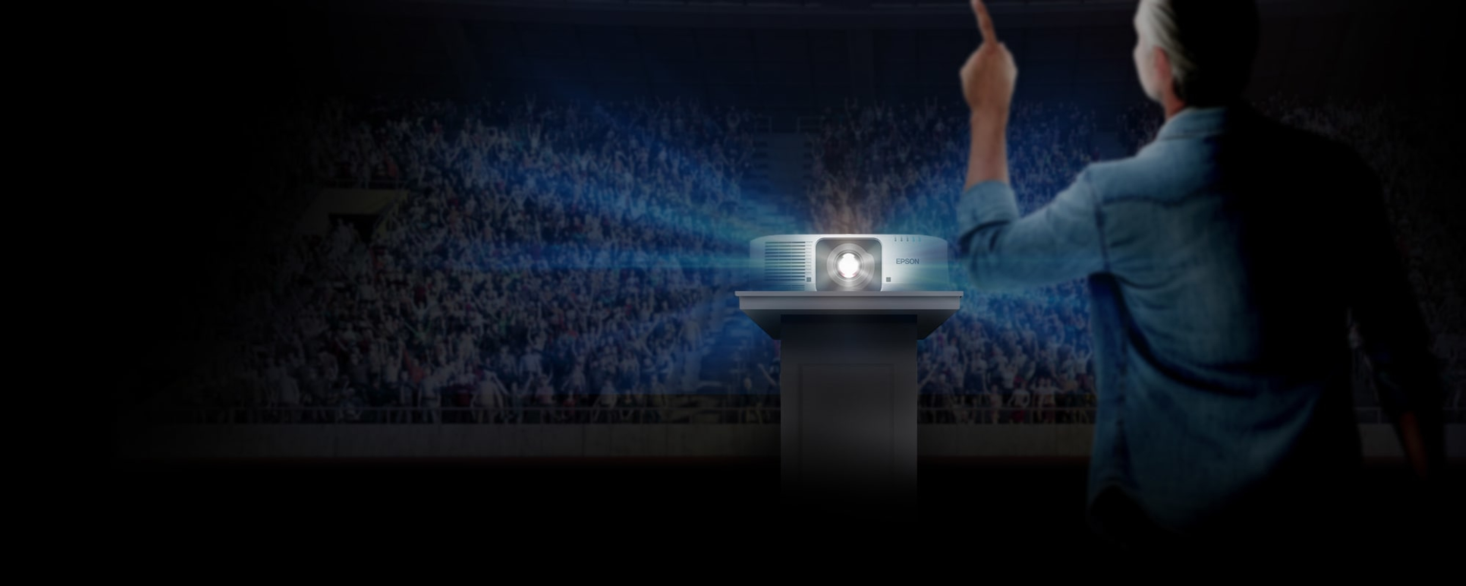 Ein Mann zeigt auf einen Projektor auf einem Ständer, der blaues Licht in ein Stadion projiziert.