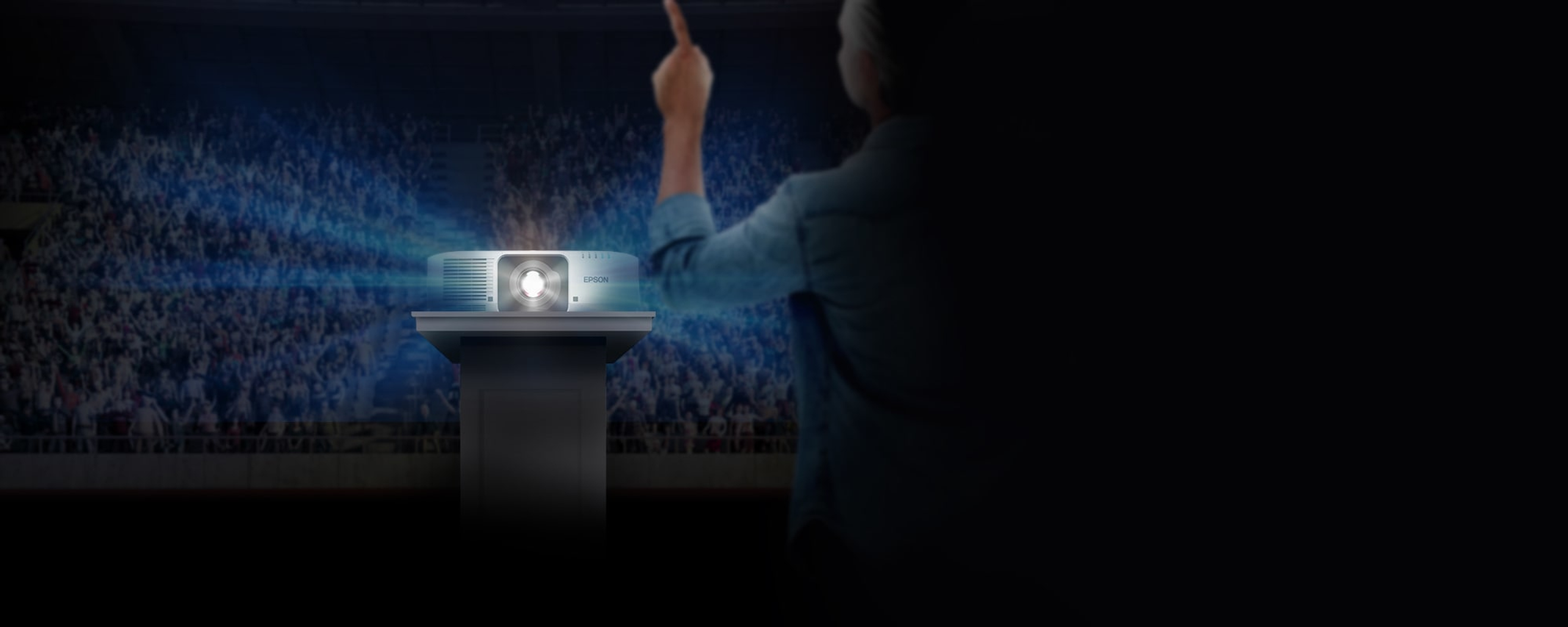Ein Mann präsentiert mit einem Projektor. Ein Lichtstrahl scheint auf ein Publikum in einem Theater.