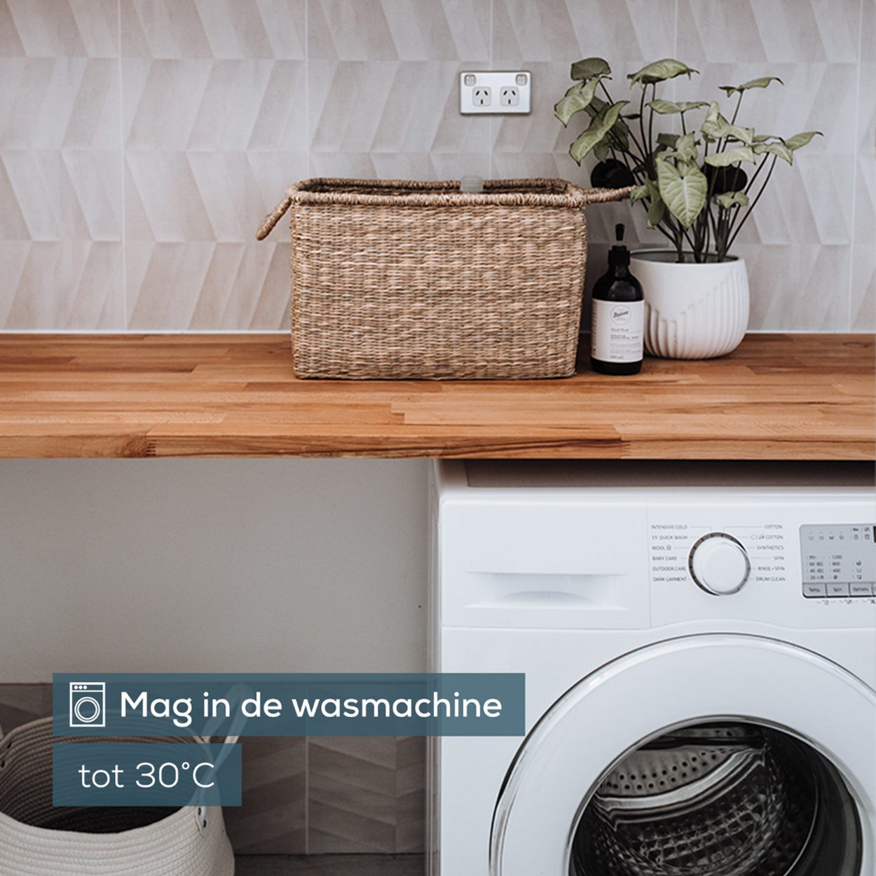 Ein Waschraum mit Waschmaschine und Holztheke. Auf der Theke stehen ein Korb und Pflanzen.