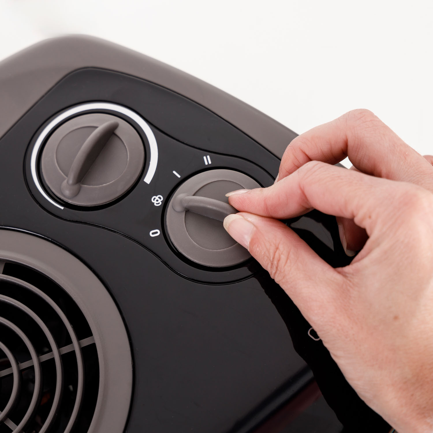 Zbliżenie czarnego i szarego urządzenia. Ręka przekręca pokrętło.