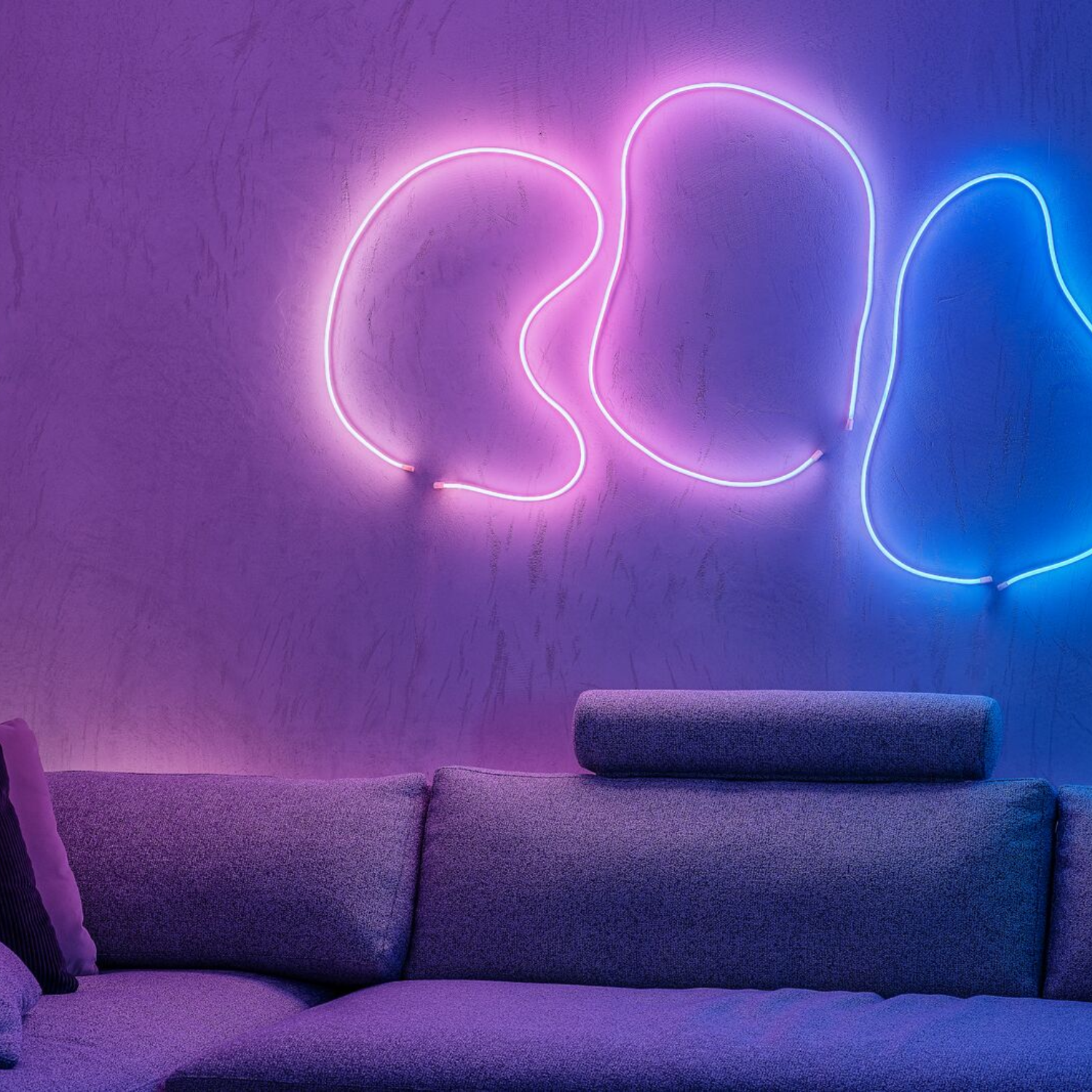 Abstrakcyjny neon na ścianie, z sofą na pierwszym planie.