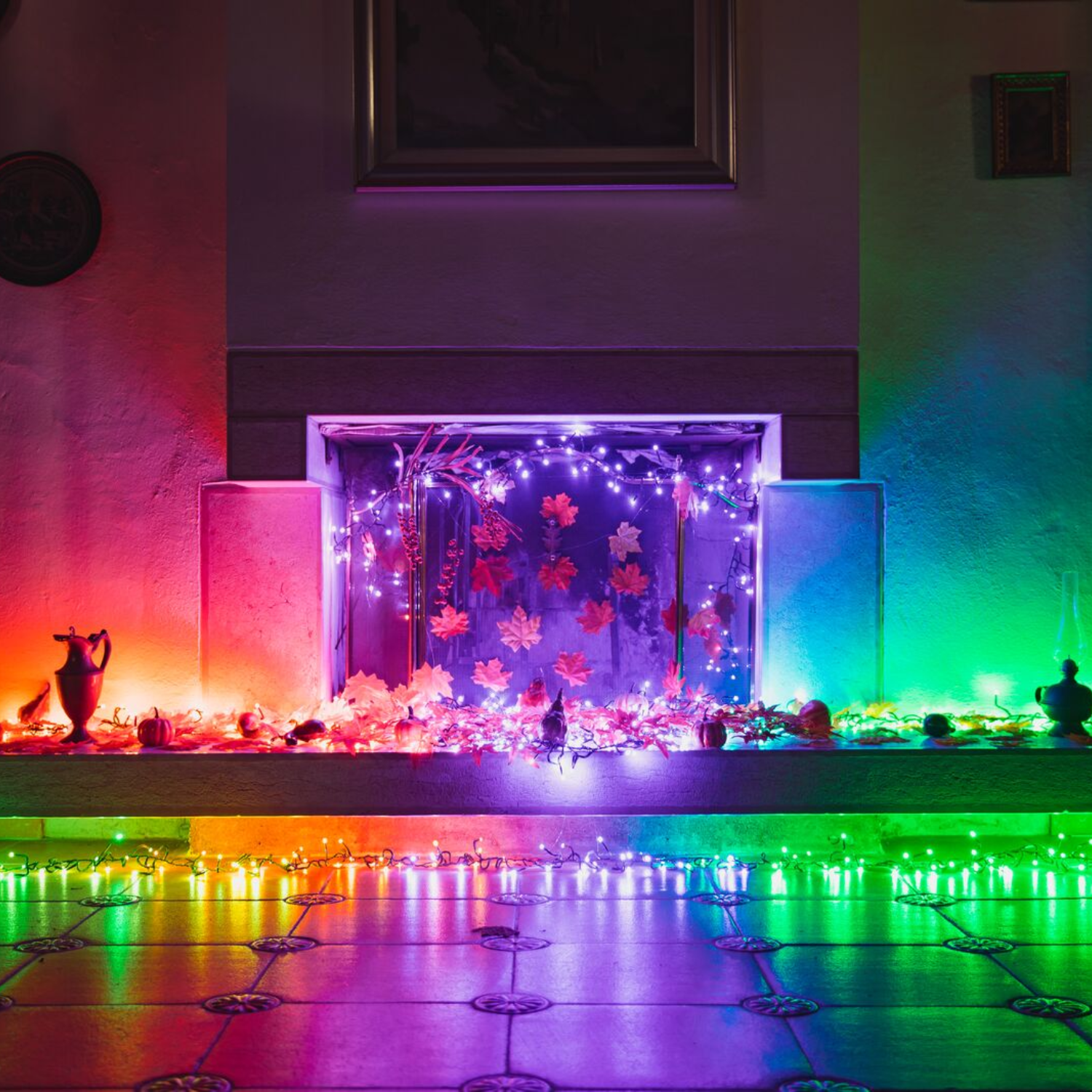 Kominek z kolorowymi światłami i jesiennymi liśćmi, tworzący świąteczną scenę.