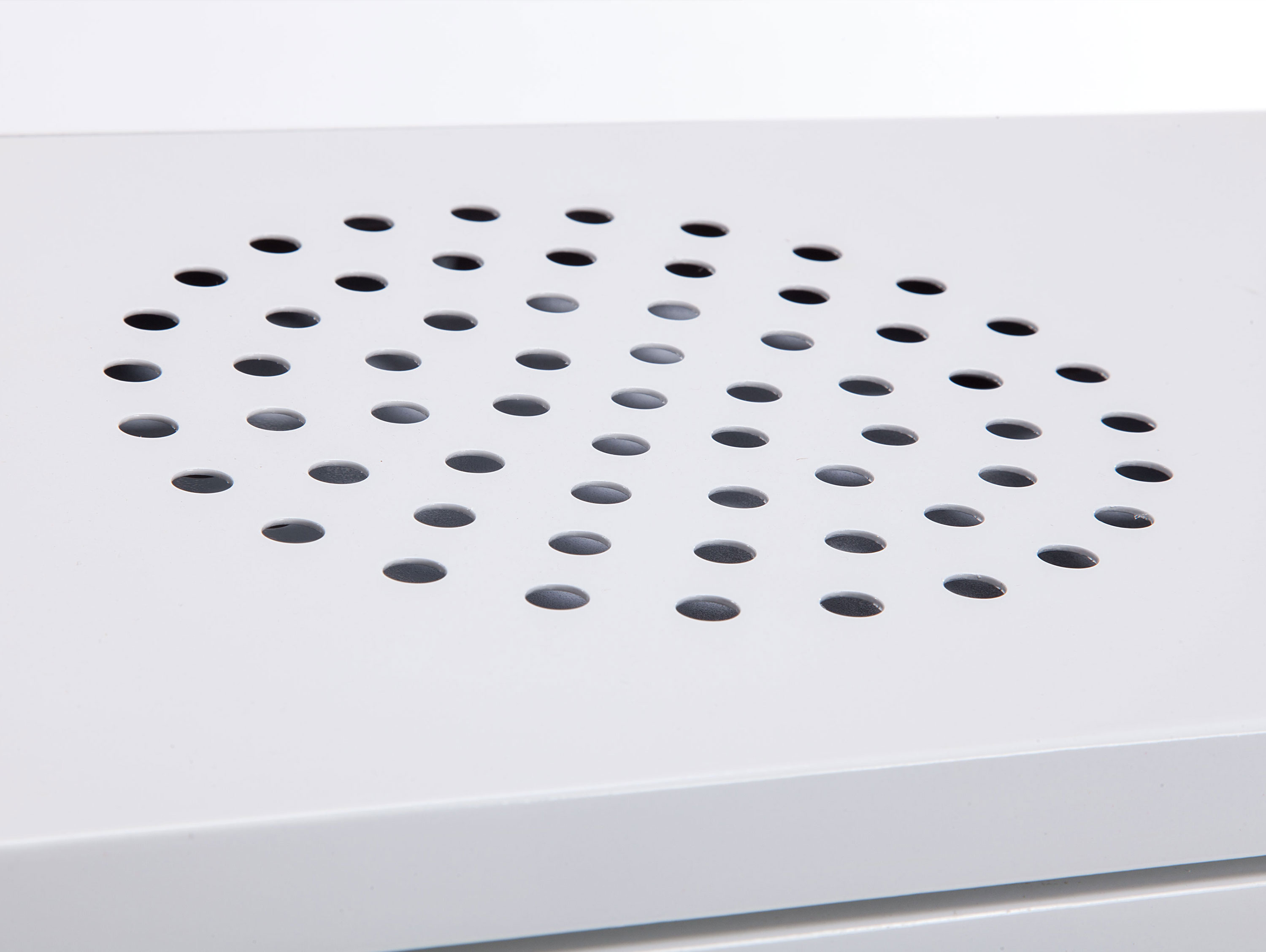 Pannello bianco con motivo ovale di piccoli fori, primo piano.