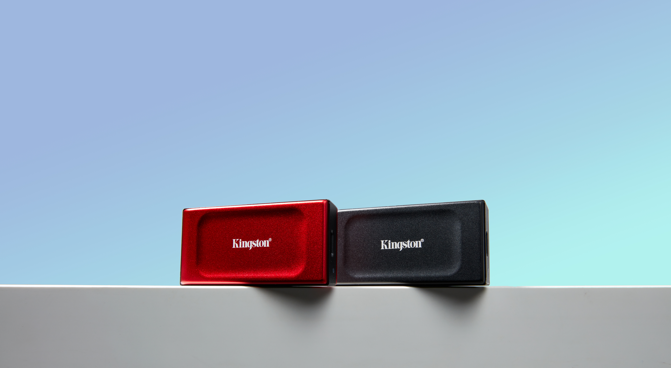 Dwa pendrive'y Kingston, czerwony i czarny, umieszczone na białej powierzchni z niebieskim tłem.