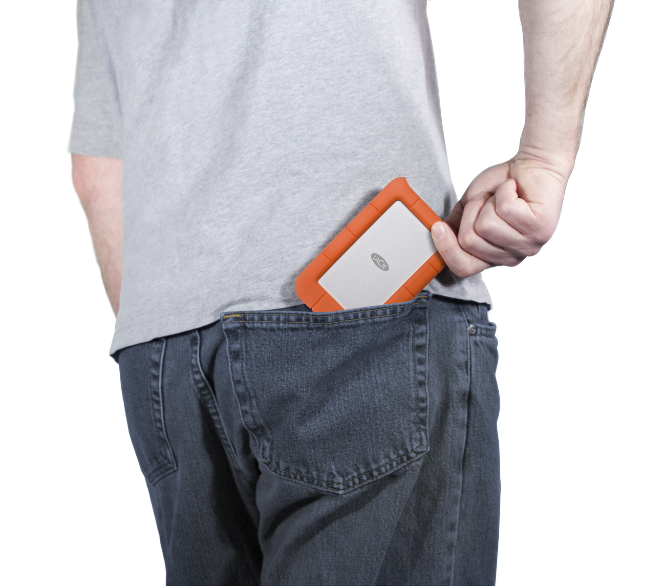 Osoba wkładająca pomarańczowy i biały dysk twardy do kieszeni niebieskich dżinsów.