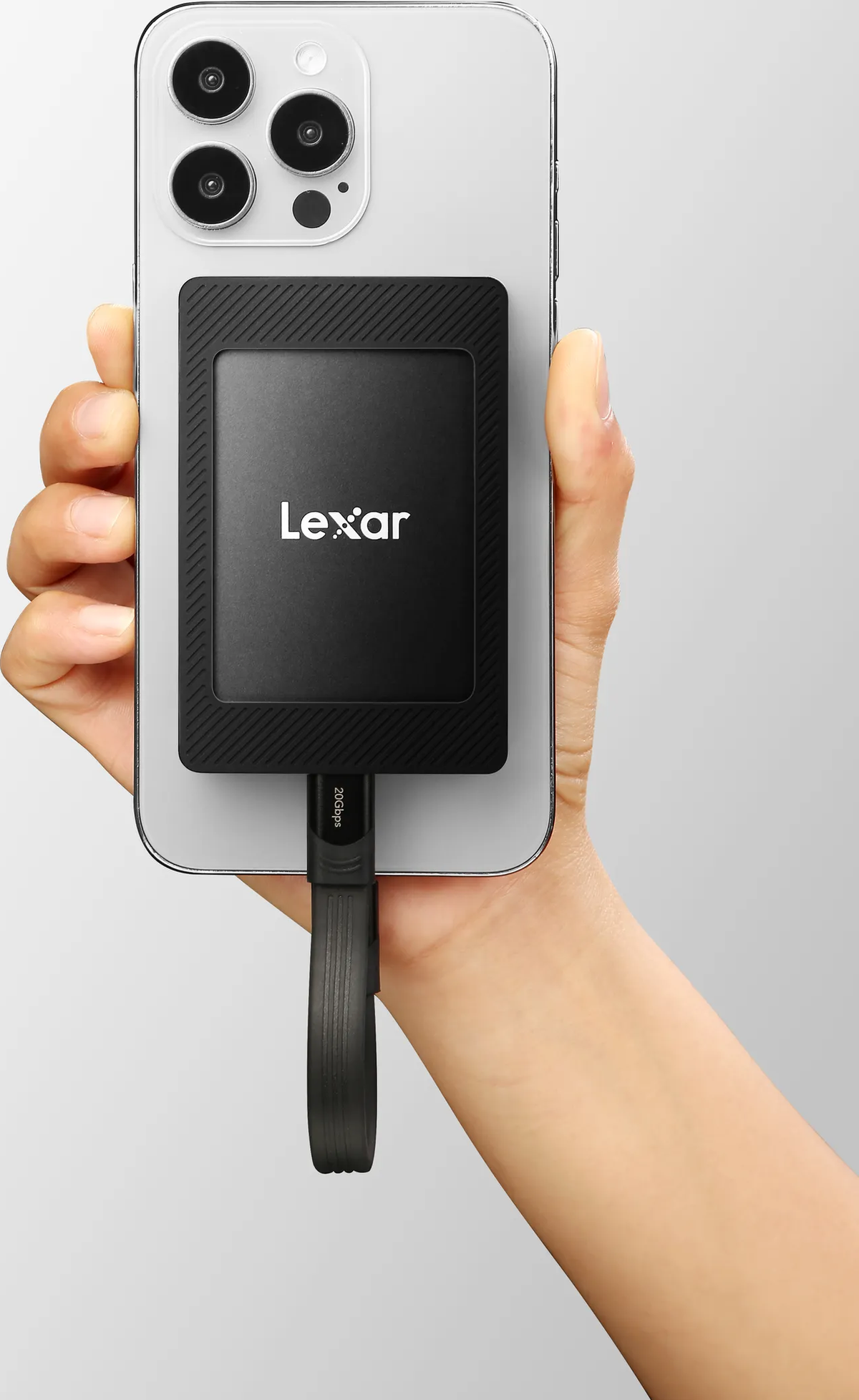 Dłoń osoby trzymająca czarny dysk SSD Lexar podłączony do telefonu. Kabel jest czarny.
