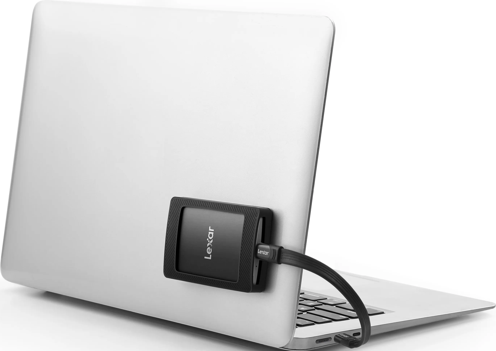 Czarny dysk SSD Lexar podłączony do srebrnego laptopa kablem USB.