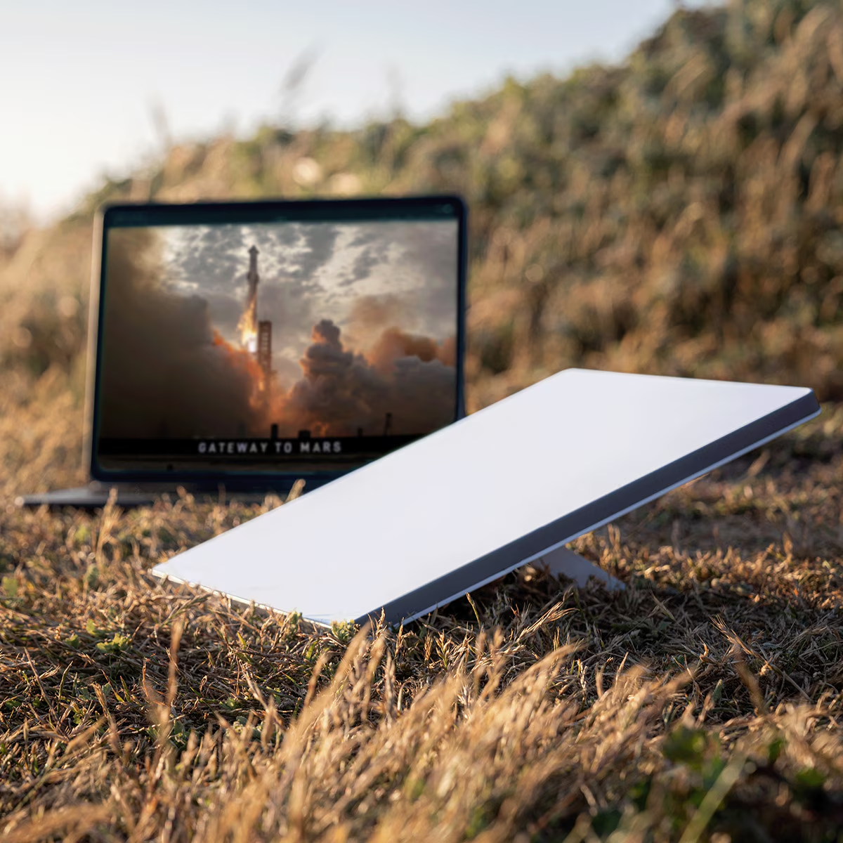 Laptop, der einen Raketenstart zeigt. Weiße Satellitenschüssel auf Gras.