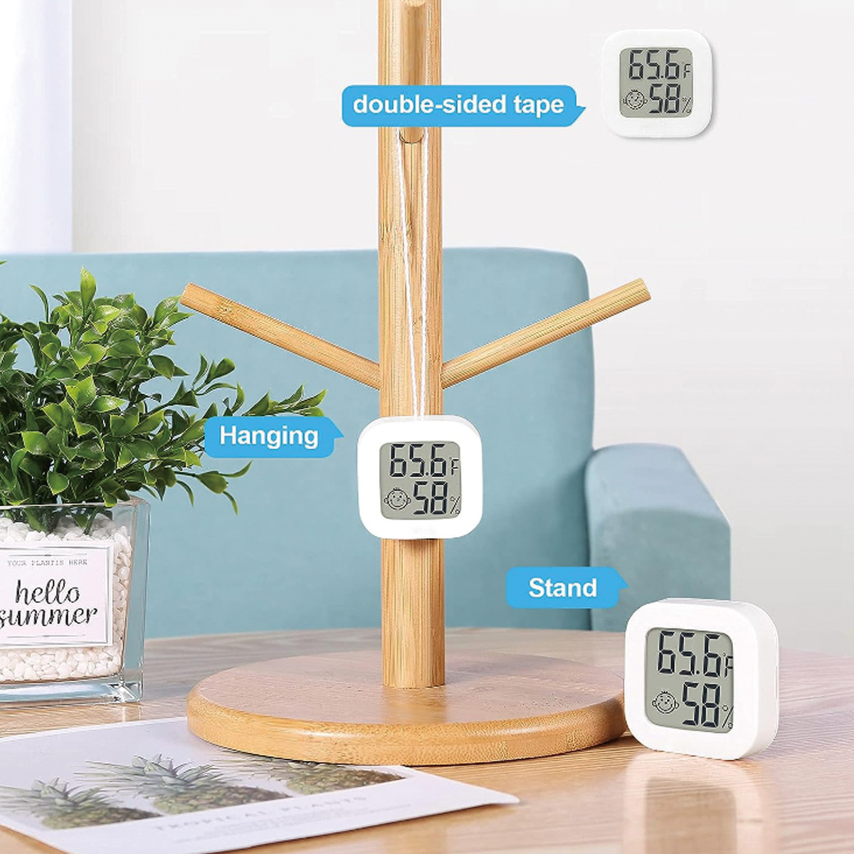 Thermometer auf einem Holzständer, mit Pflanze und blauer Couch im Hintergrund.