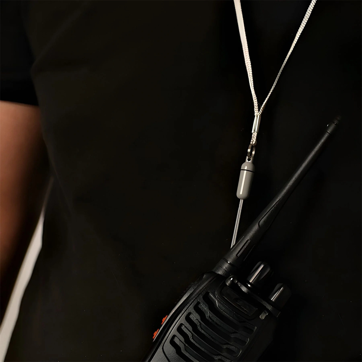 Eine Person trägt ein Lanyard mit einem Funkgerät an einem schwarzen Hemd.