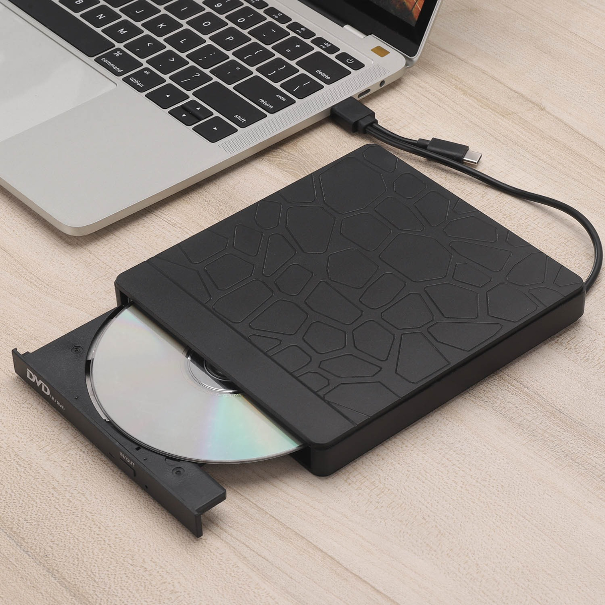 Ein Laptop, der mit einem schwarzen externen DVD-Laufwerk mit eingelegter Disc verbunden ist.