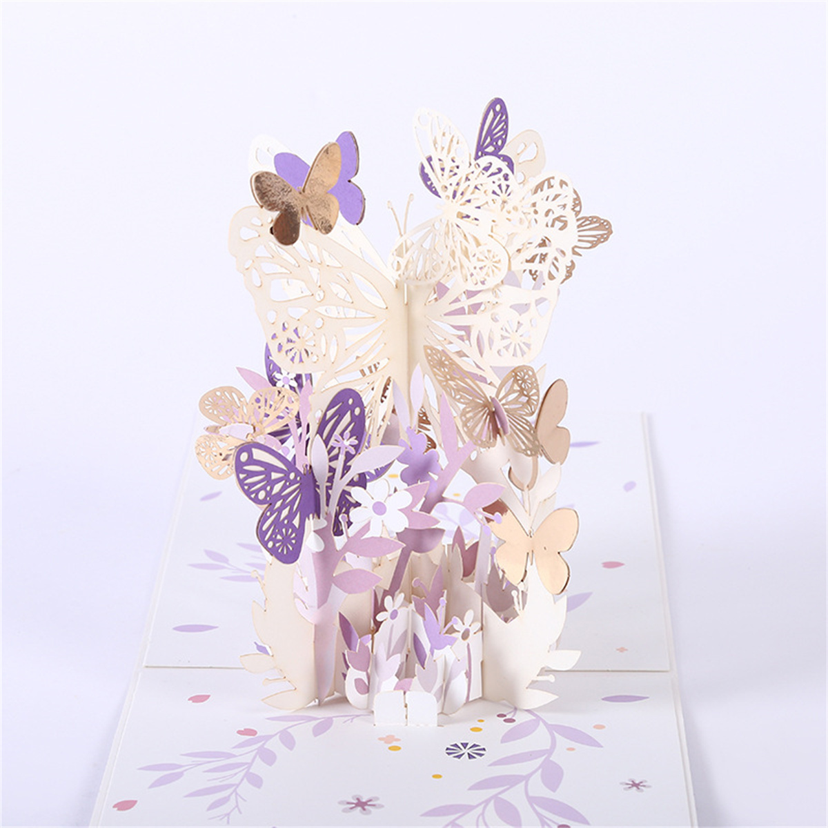 Eine Pop-up-Karte mit Papier-Schmetterlingen und Blumen in Weiß und Lila.