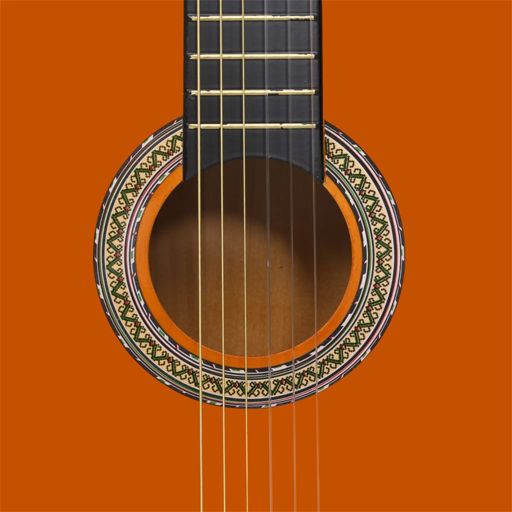 Nahaufnahme des Schalllochs einer klassischen Gitarre. Die Gitarre ist orange mit dekorativem Rand.