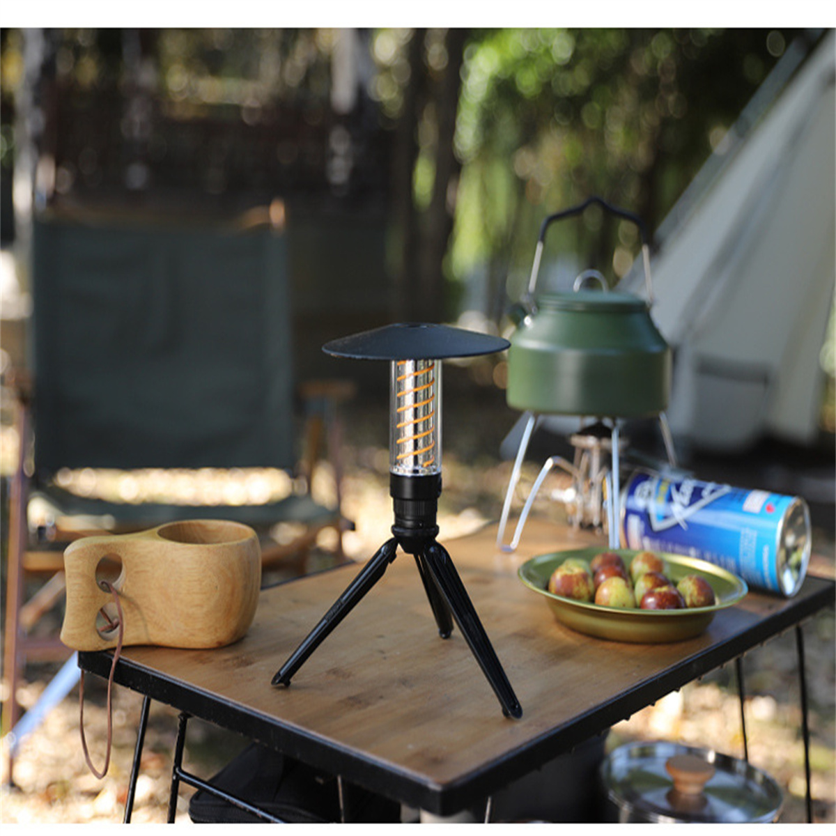 Camping-Szene mit Laterne, Holzbecher und kleiner Pfanne auf einem Tisch.