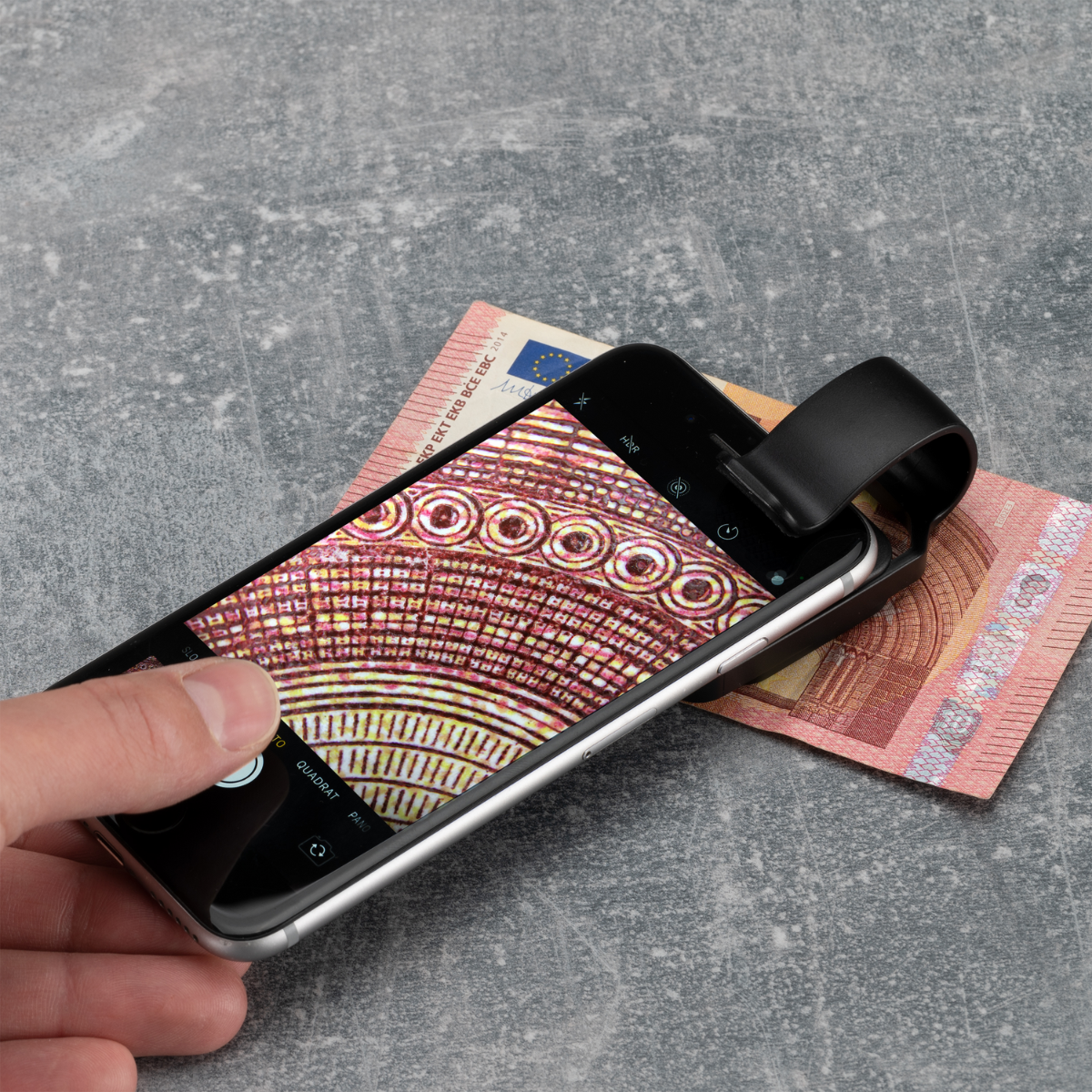 Smartphone con lente de aumento sobre un billete de euro.