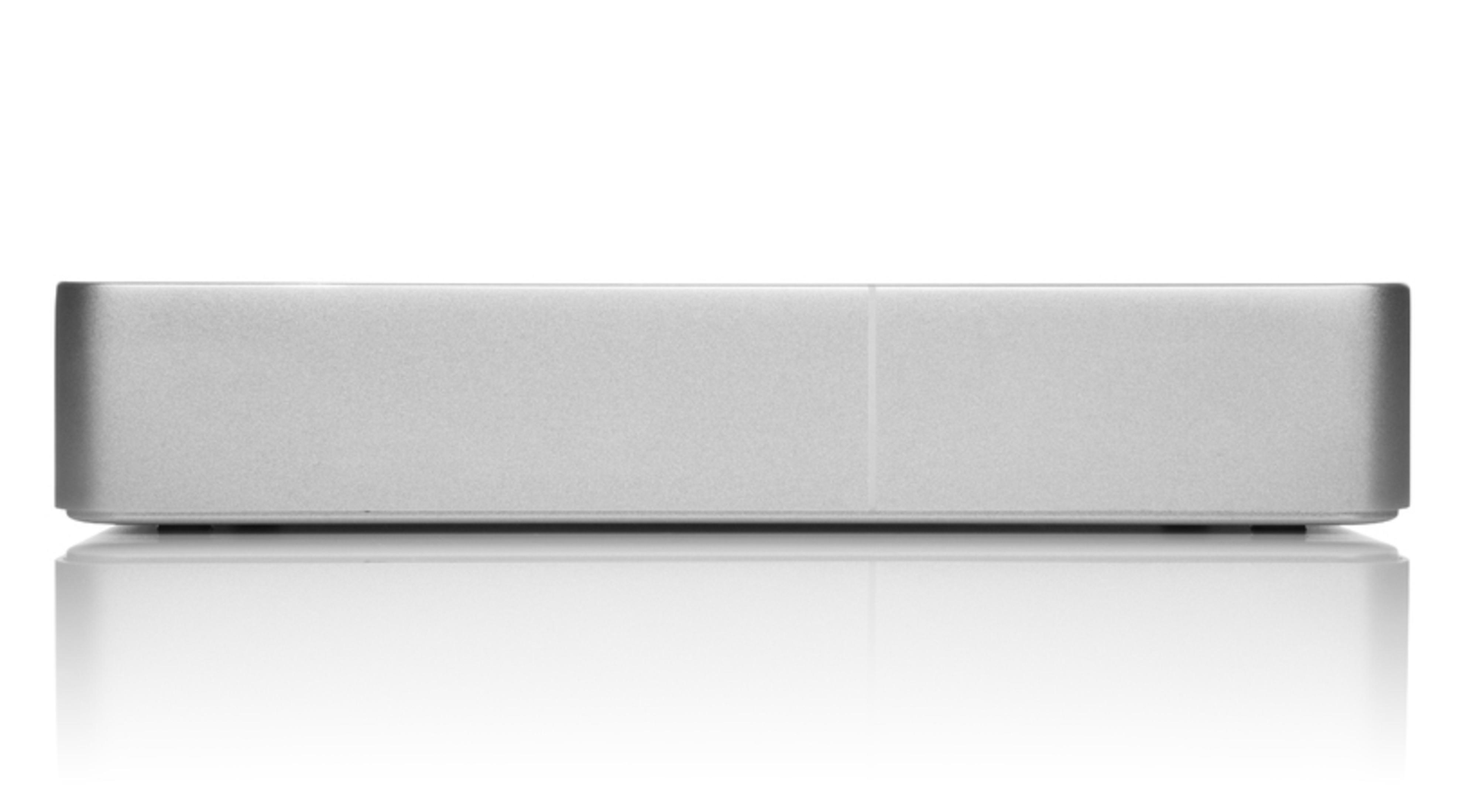 Srebrne prostokątne urządzenie na białej, odbijającej światło powierzchni. Widok z góry, czyste linie.