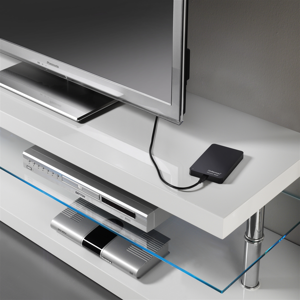 Biała błyszcząca półka z telewizorem, odtwarzaczem DVD i podłączonym dyskiem twardym.