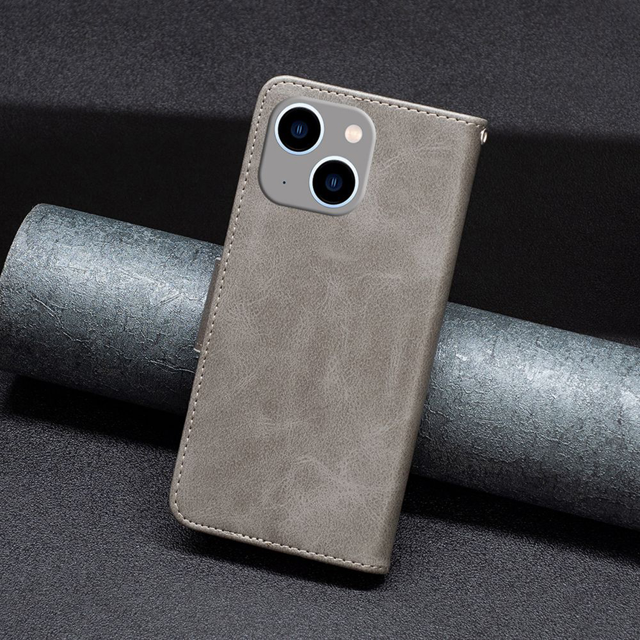 Grijze leren telefoonhoes met telefoon, met camera. Telefoon ligt op een grijs oppervlak.