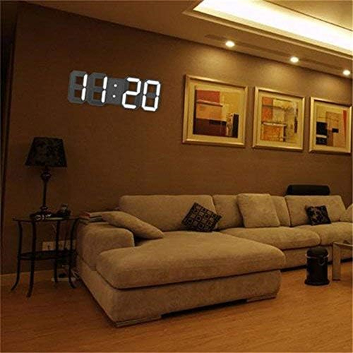 Moderne Digitaluhr an einer braunen Wand, über einem Sofa und neben einer Tischlampe.