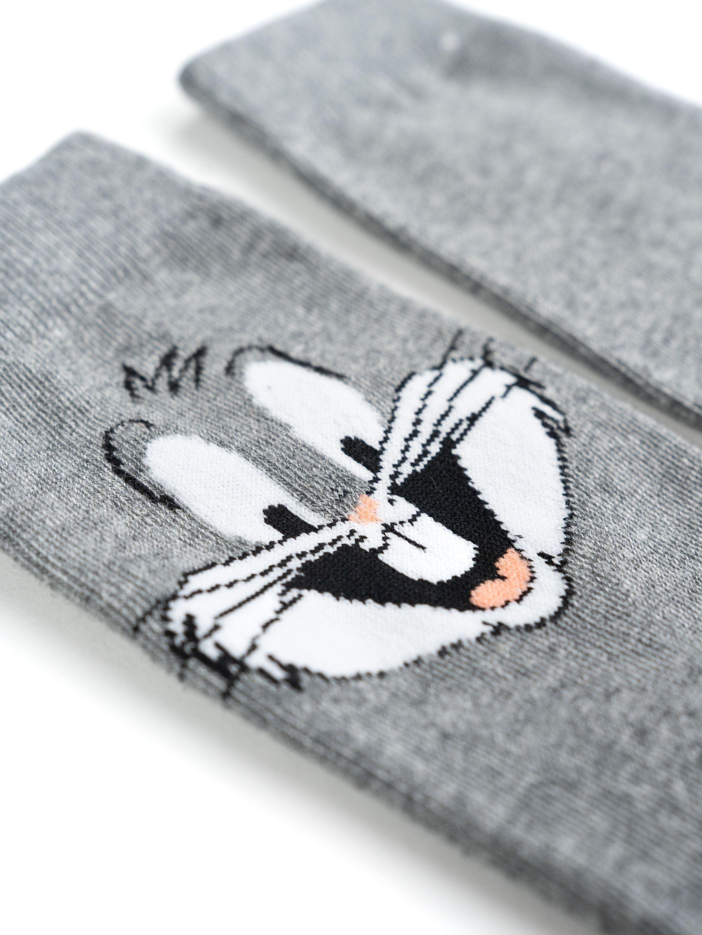 Nahaufnahme von zwei grauen Bugs-Bunny-Socken mit seinem Gesicht darauf.