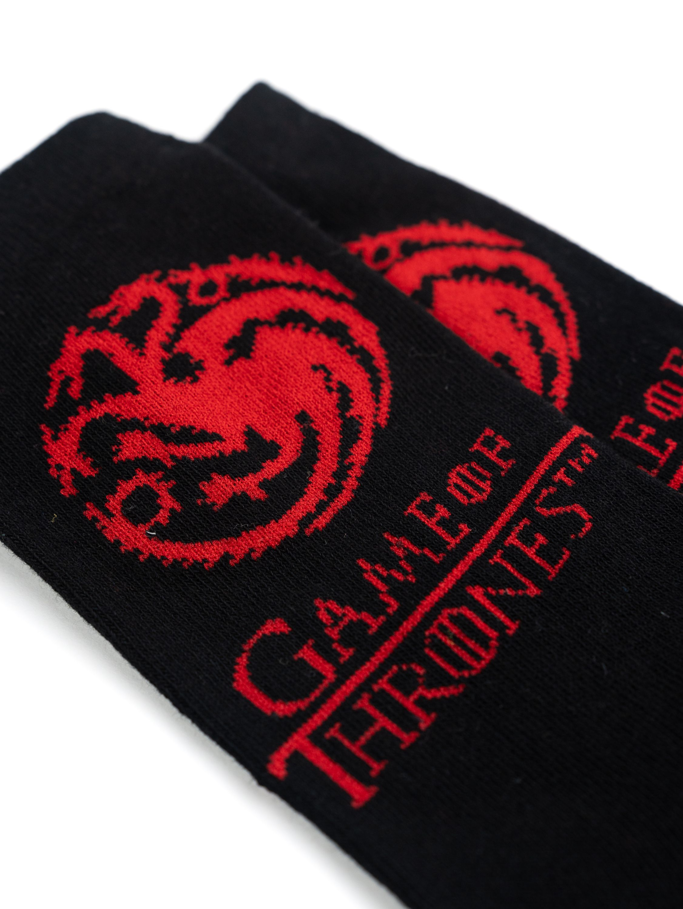 Nahaufnahme von zwei schwarzen Game of Thrones Socken mit dem Haus Targaryen Symbol.