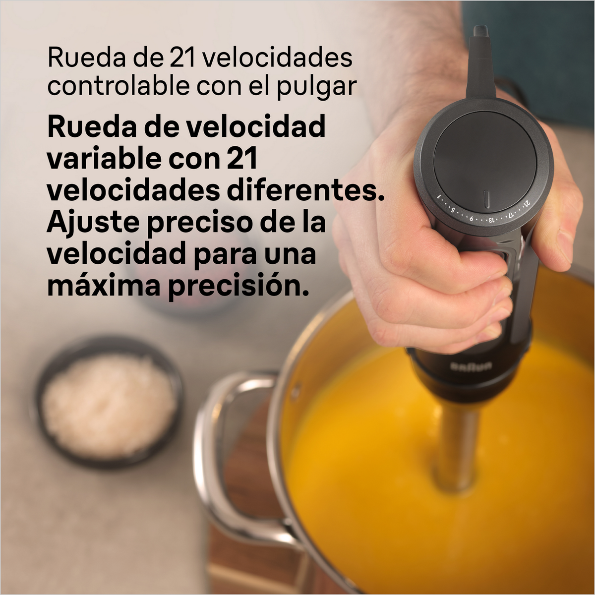 Ręka trzymająca blender ręczny, miksująca zupę w garnku, z regulacją prędkości.