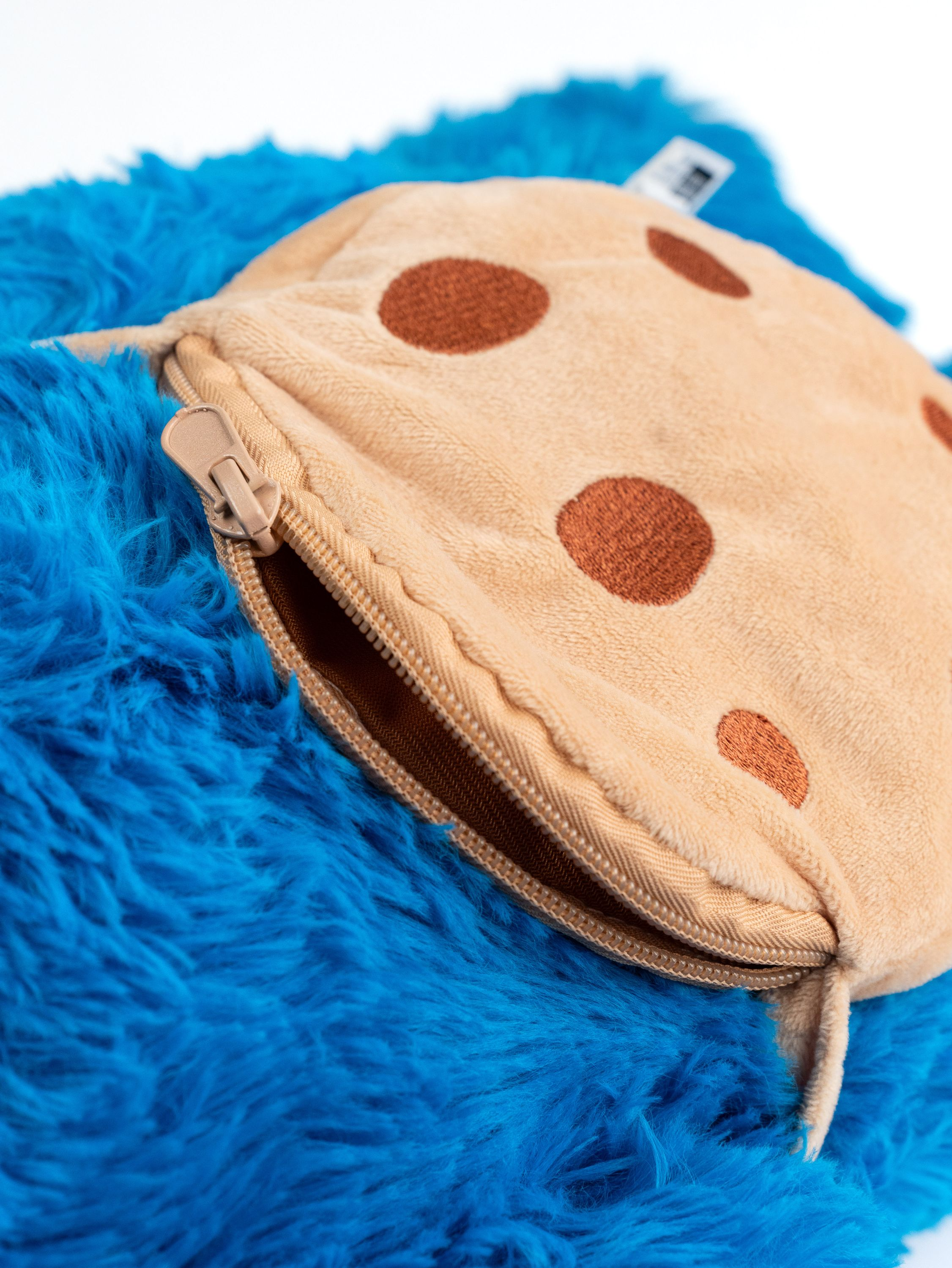 Krümelmonster-Plüschtier mit Keks-Tasche. Blaues Fell, brauner Keks.