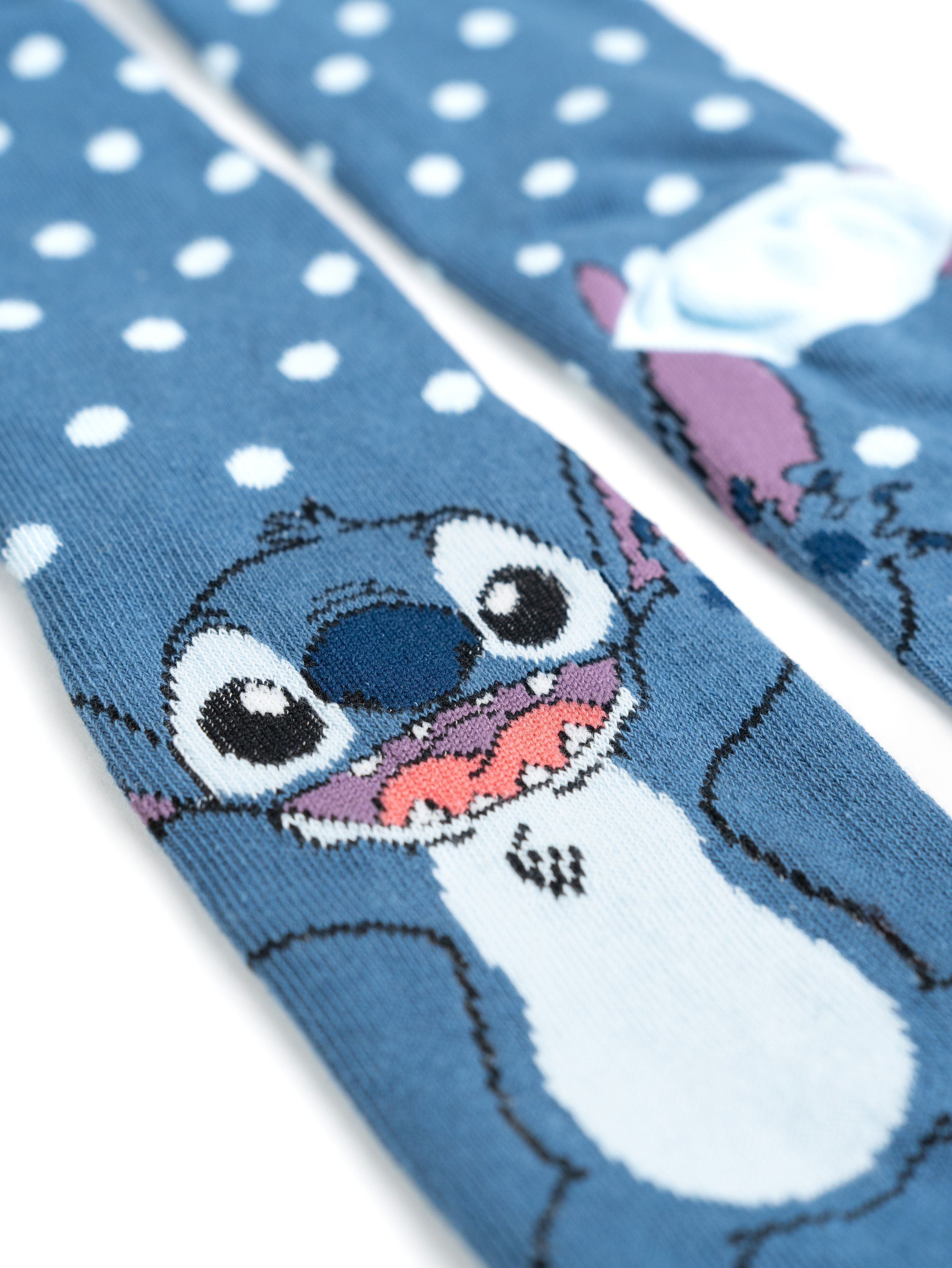 Zwei blaue Stitch-Socken mit weißen Punkten und Stitchs Gesicht. Die Socken sind auf weißem Hintergrund.