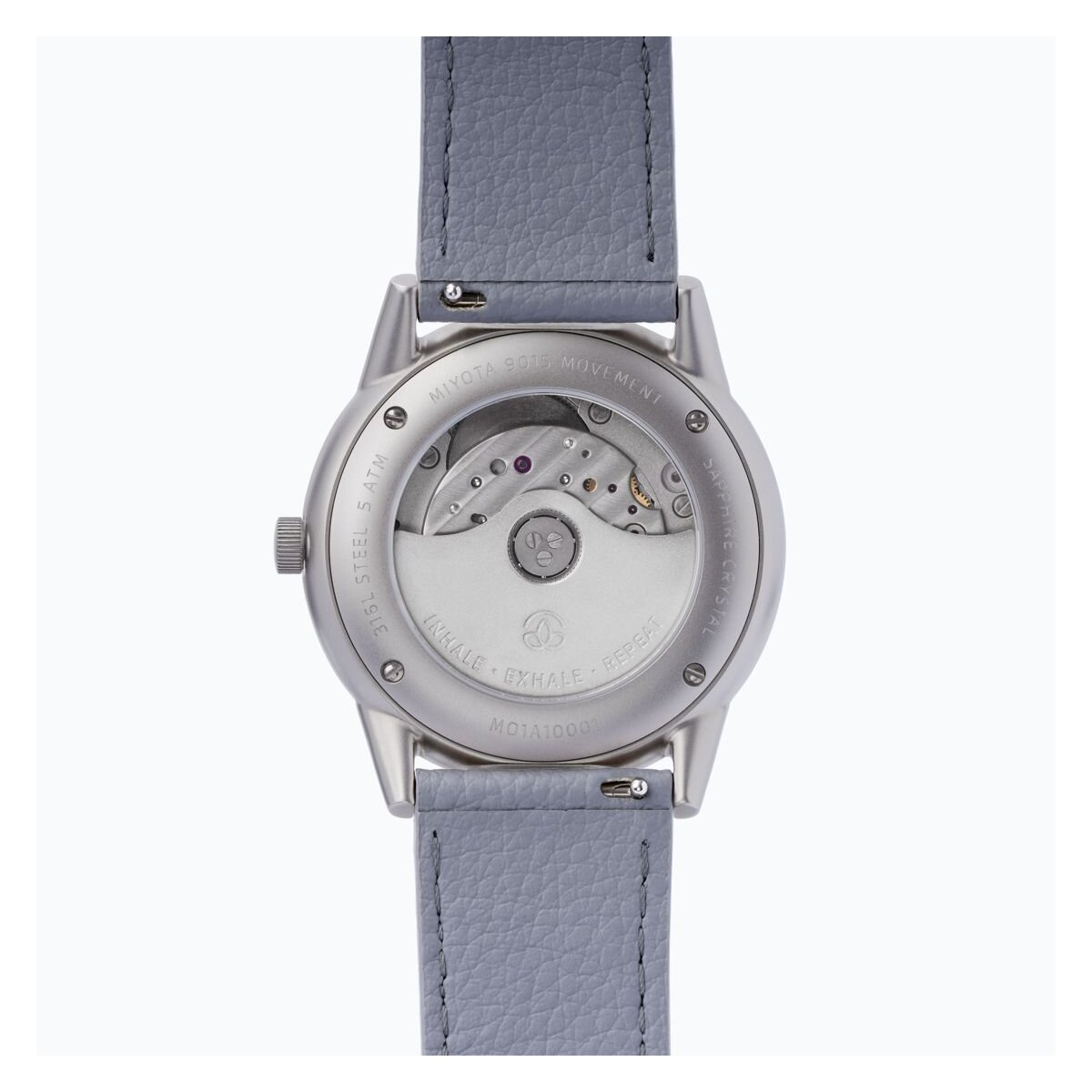 Die Rückseite einer silbernen Uhr mit grauem Lederarmband, die den inneren Mechanismus der Uhr zeigt.