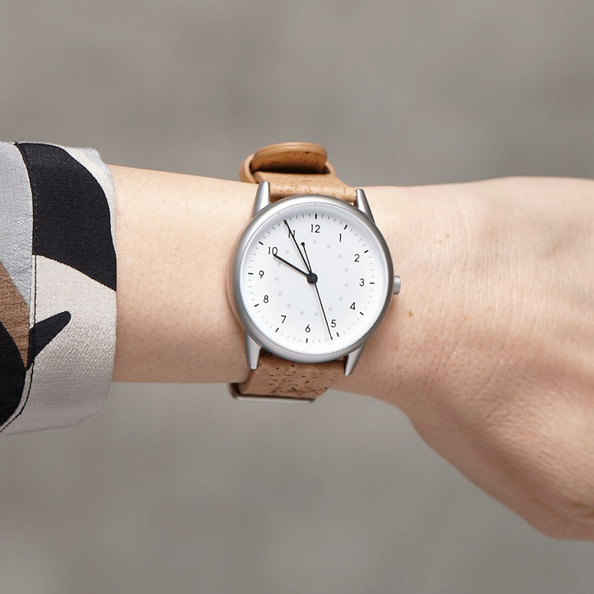 Orologio con quadrante bianco, cinturino in sughero, su un polso.