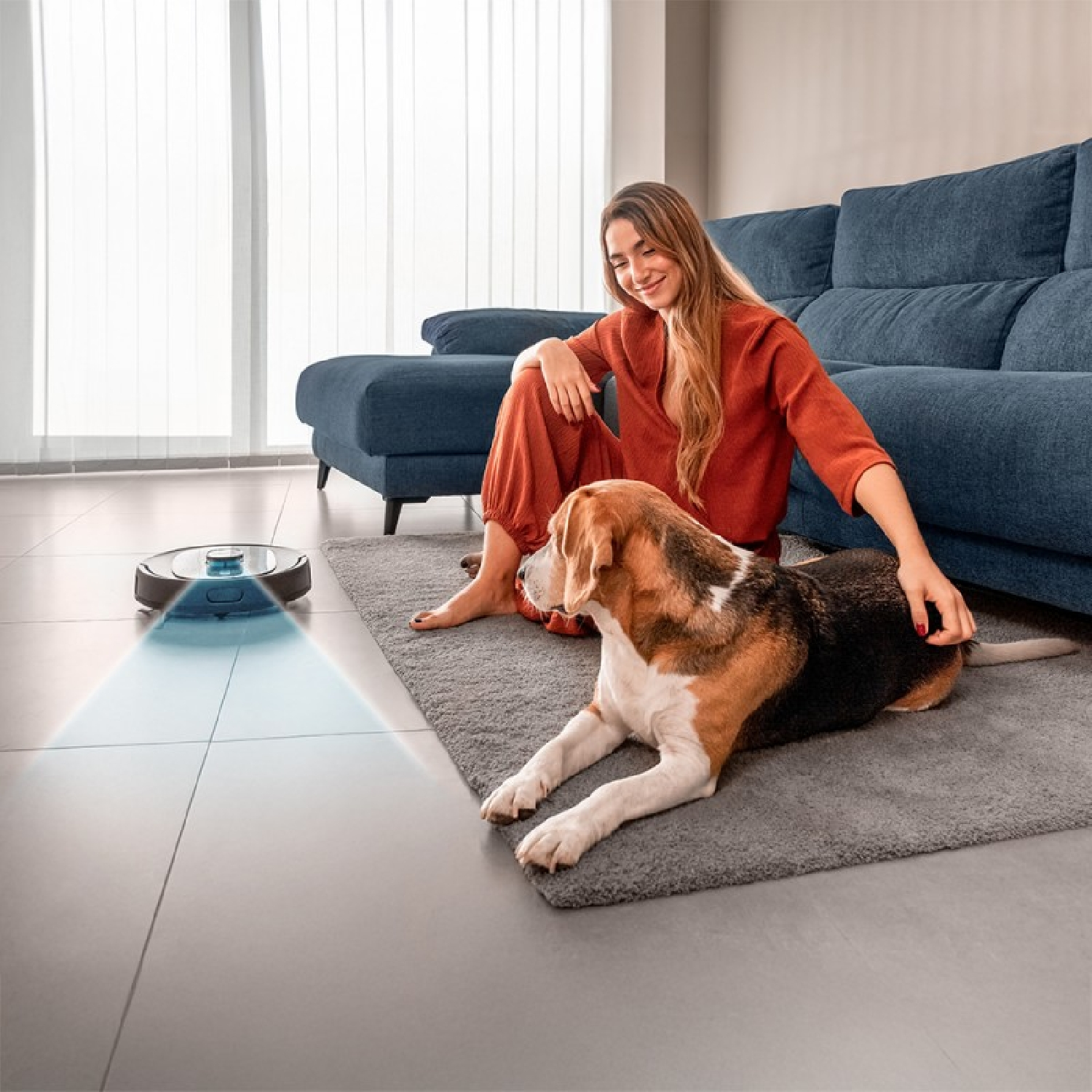 Vrouw en beagle op een kleed. Een robotstofzuiger is in de buurt.
