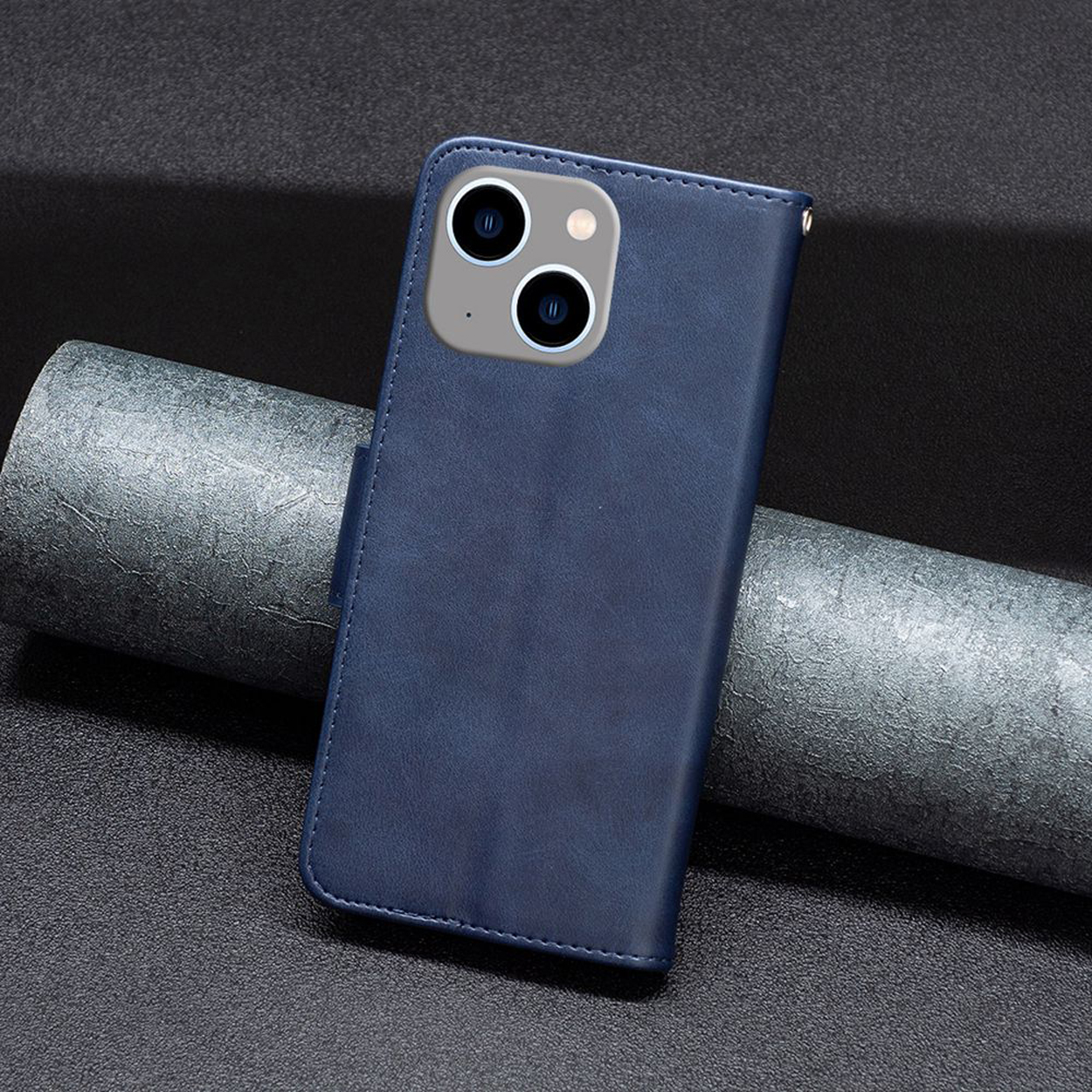 Donkerblauwe leren telefoonhoes, gesloten, met camera-uitsparing, op een donker oppervlak.