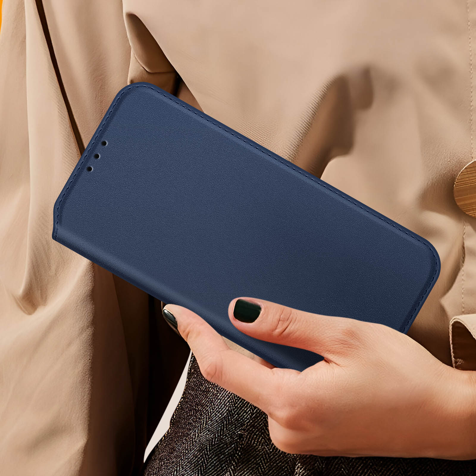 Mano di donna che tiene una custodia per telefono in pelle blu navy chiusa. La custodia è chiusa.