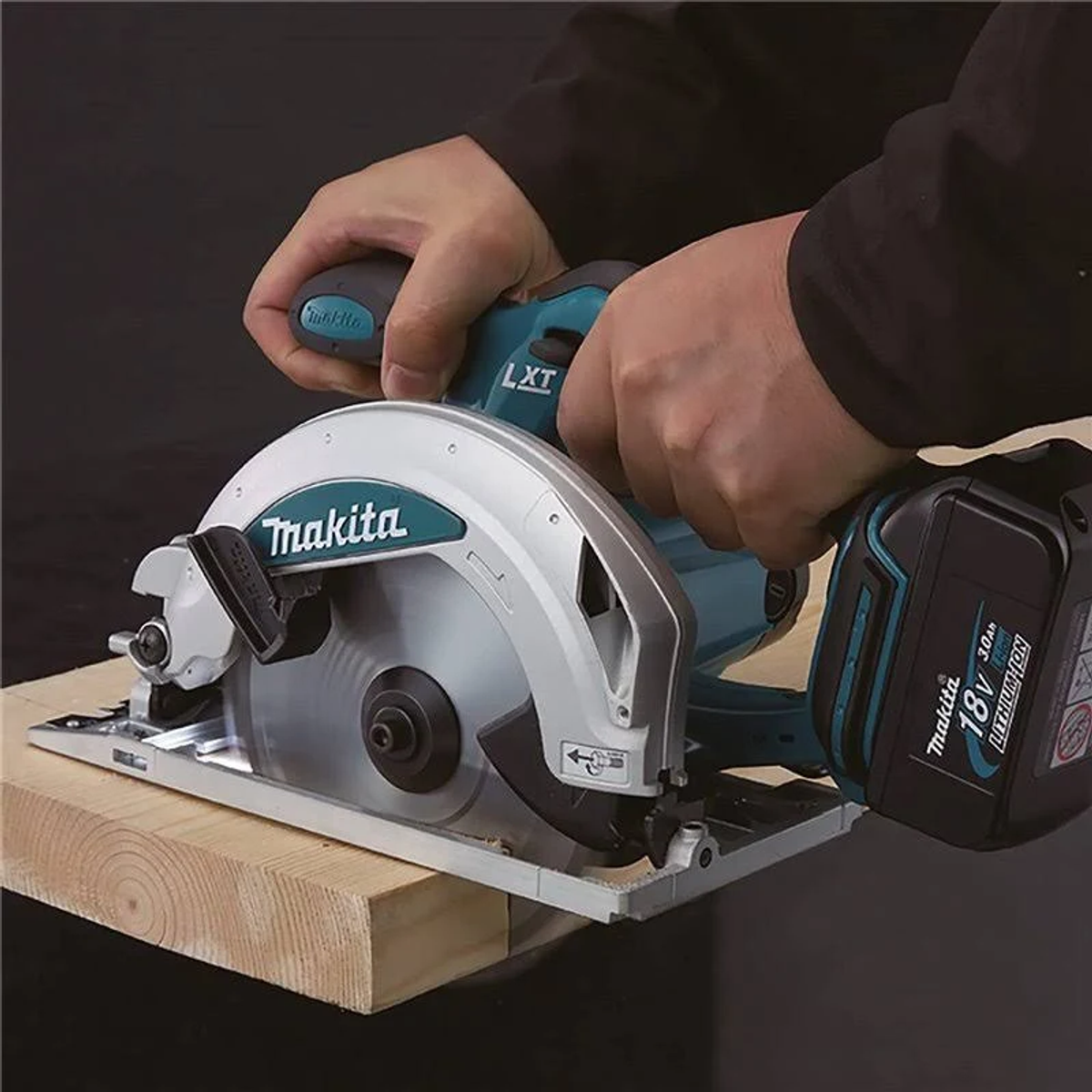 Een persoon snijdt hout met een Makita cirkelzaag op een houten plank.