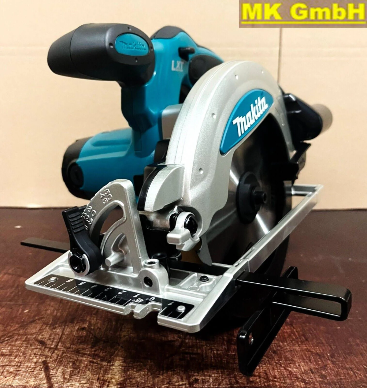 Een Makita cirkelzaag. Hij is blauwgroen en zilver, op een donker houten oppervlak.