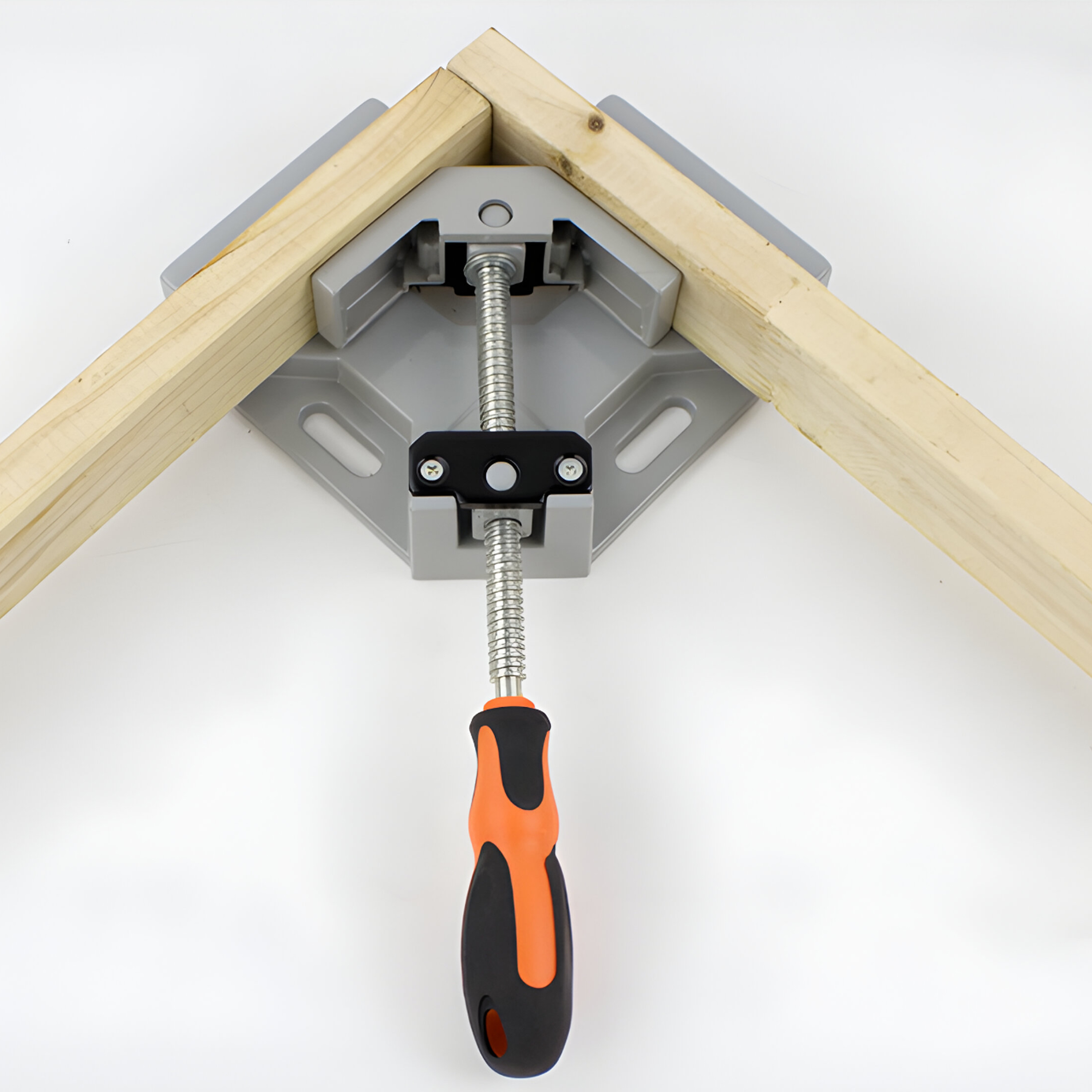 Eine Eckzwinge, die zwei Holzstücke hält. Sie hat einen orangefarbenen und schwarzen Griff.