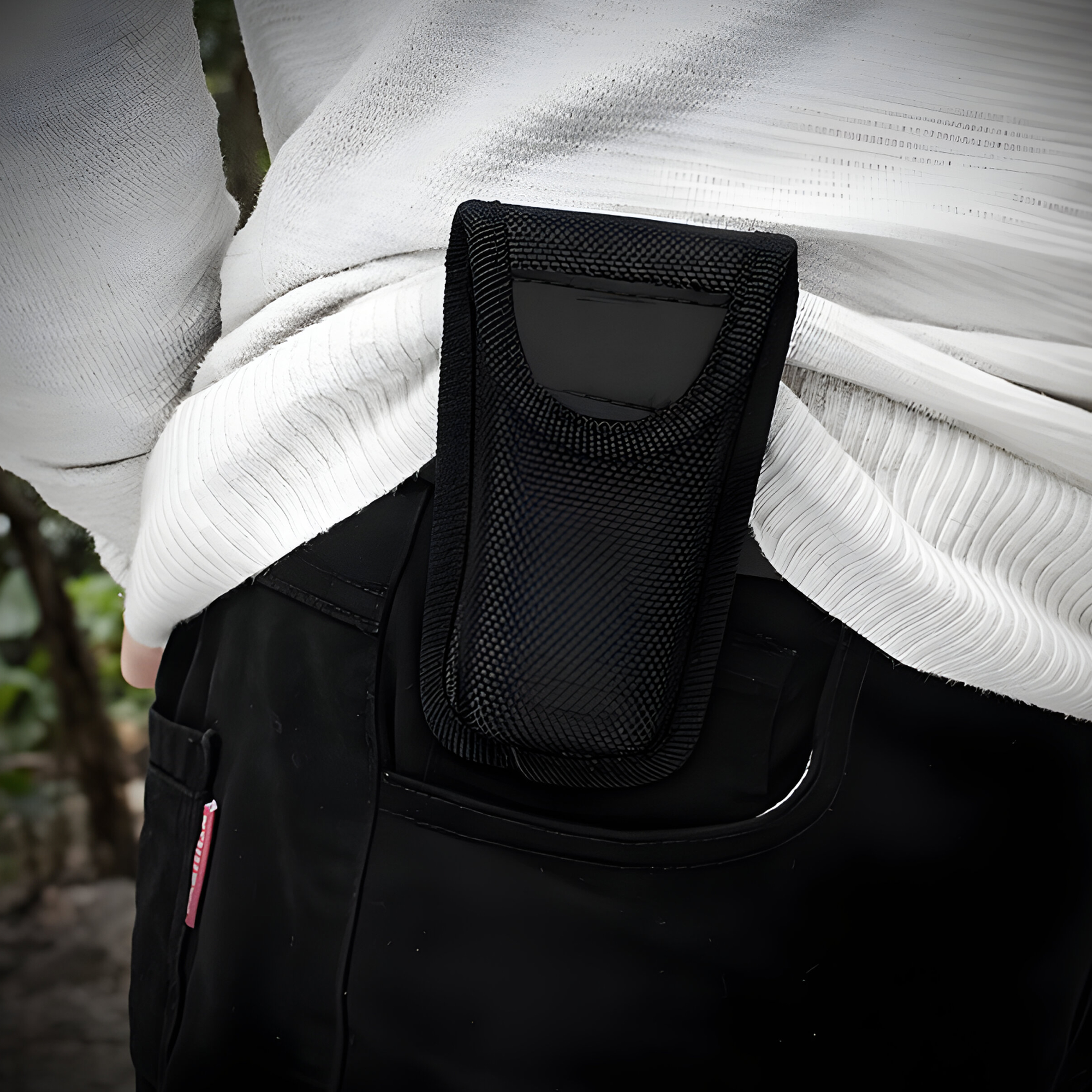 Eine schwarze Telefonholster, die an einer schwarzen Hosentasche befestigt ist.