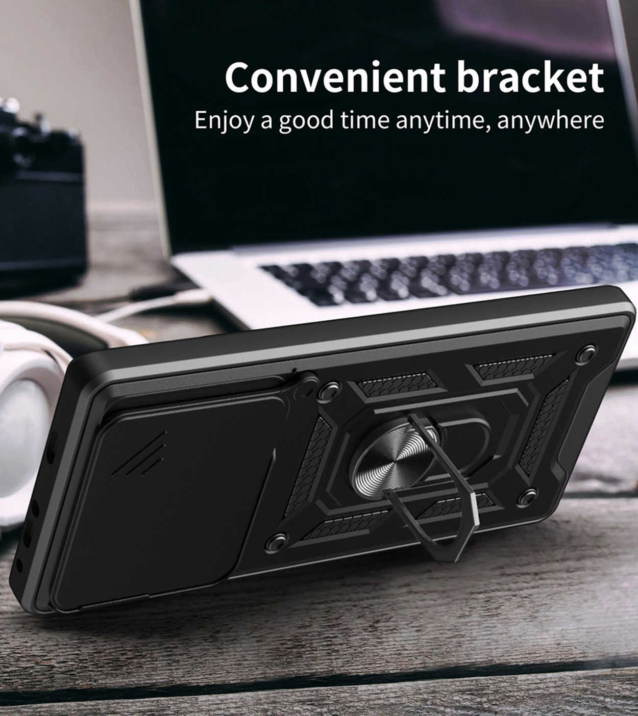 Coque de téléphone noire avec support de bague. La coque est sur une table devant un ordinateur portable.