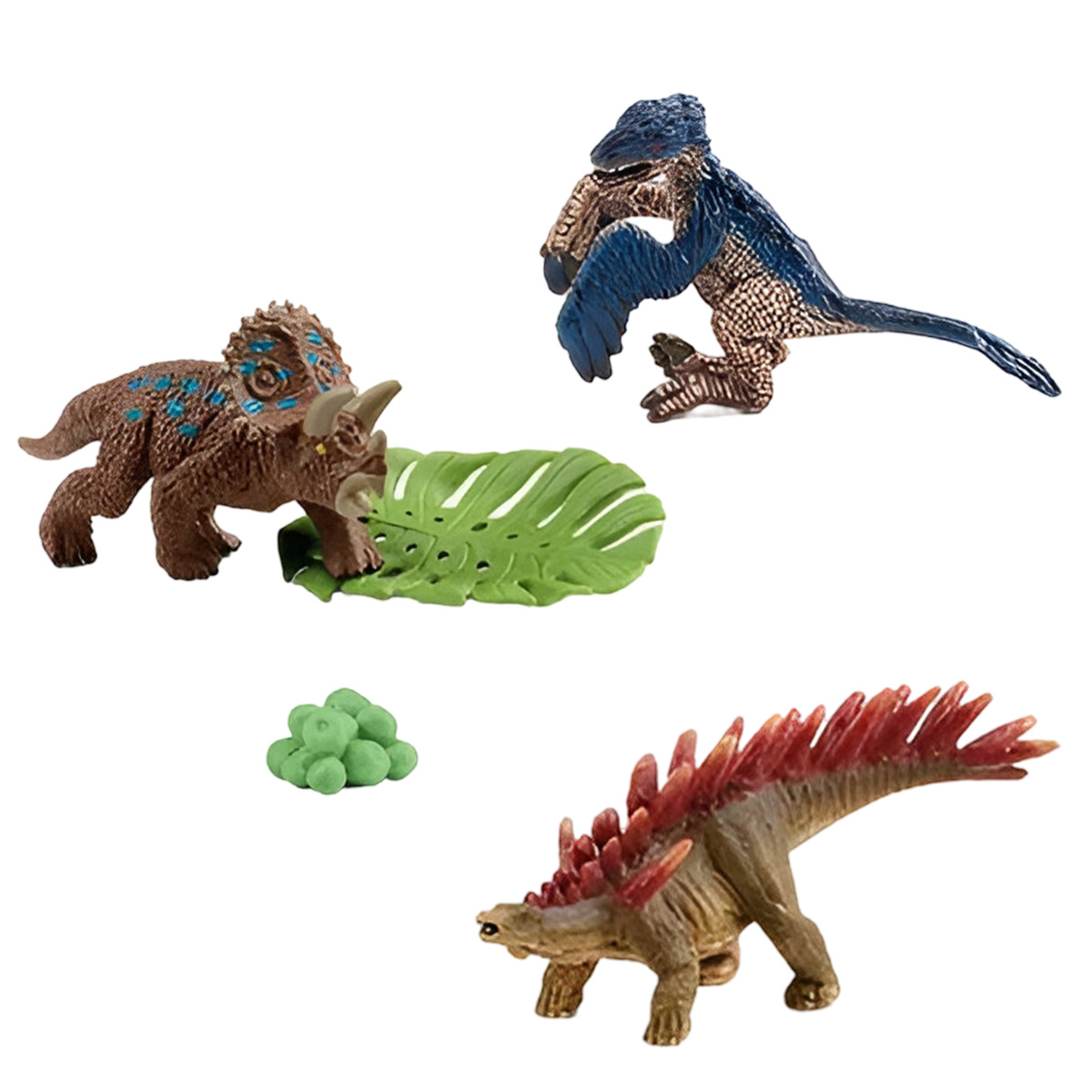 Drei Dinosaurierfiguren: Triceratops, Velociraptor und Stegosaurus. Grünes Blatt und Felsen auf weißem Hintergrund.