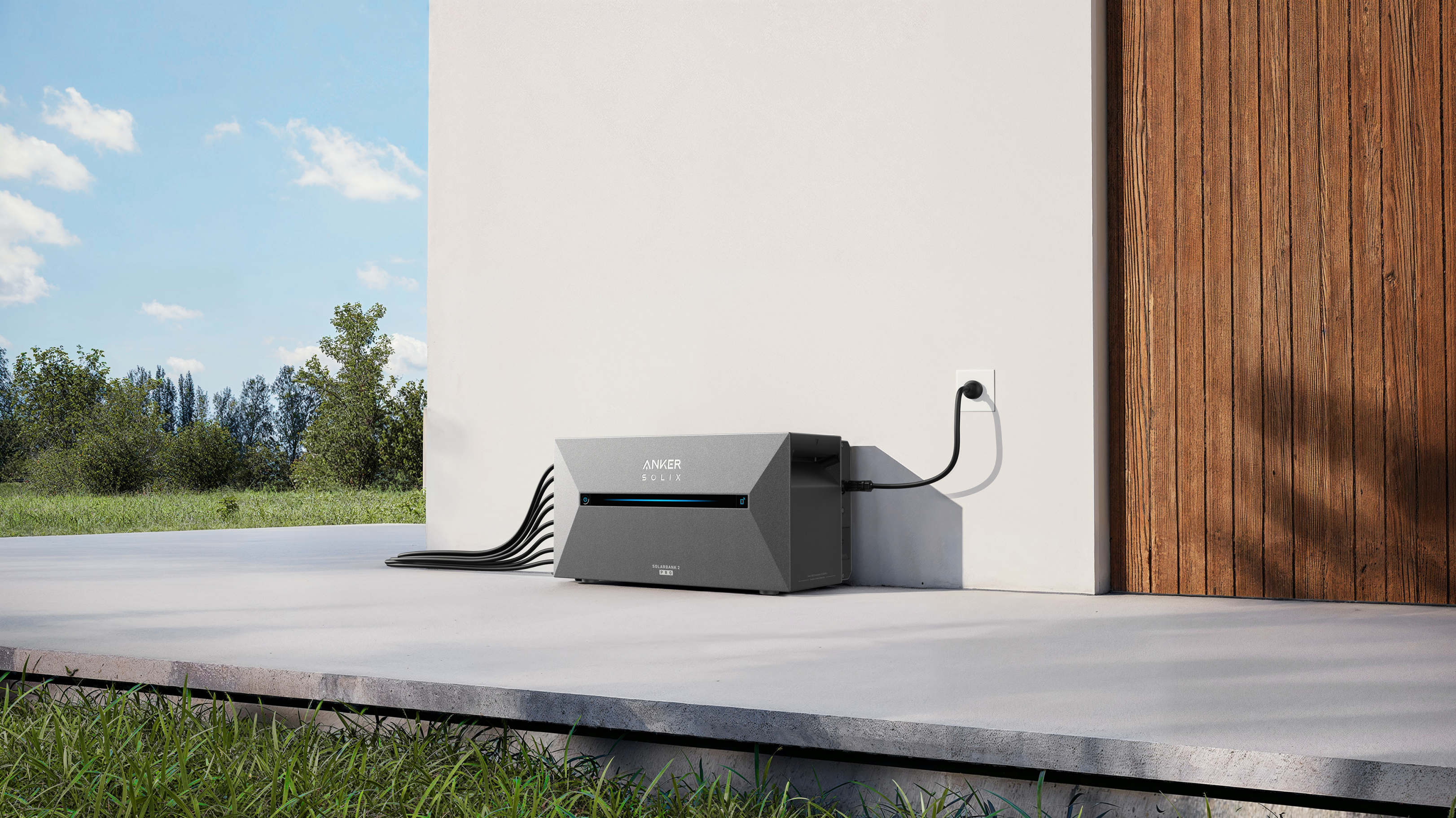 Stacja zasilania Anker przed białym domem z drewnianymi drzwiami. Podłączony kabel.