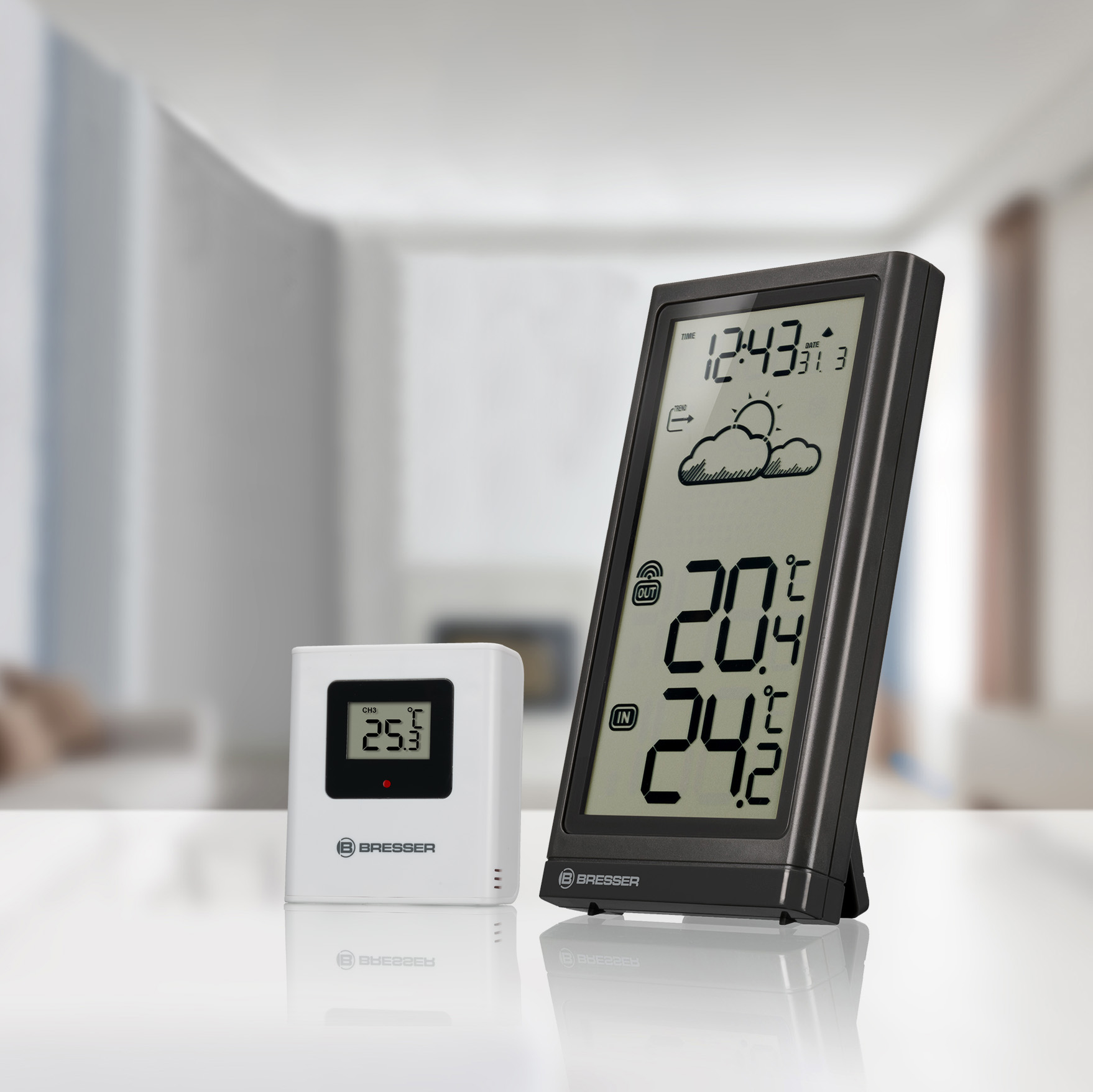 Wetterstation mit Display und kleinerem Sensor, auf einem Tisch.