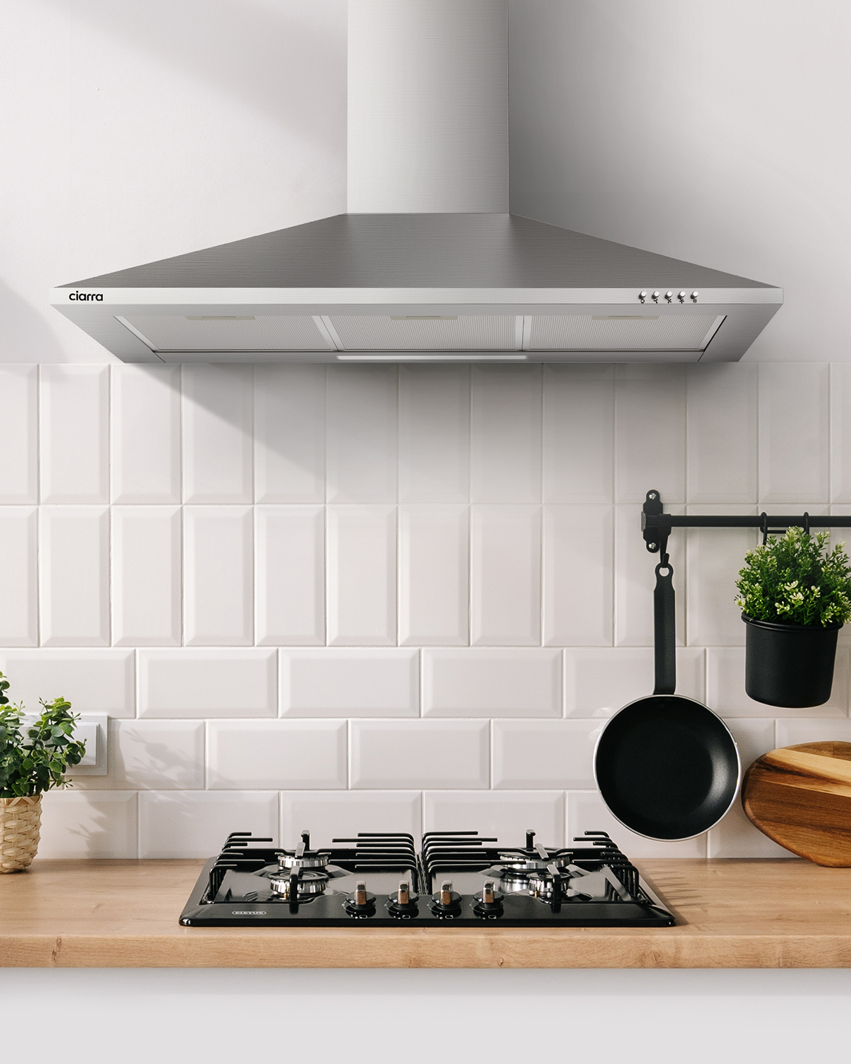 Keuken interieur. RVS afzuigkap, zwart kookveld, witte tegel backsplash, en planten.